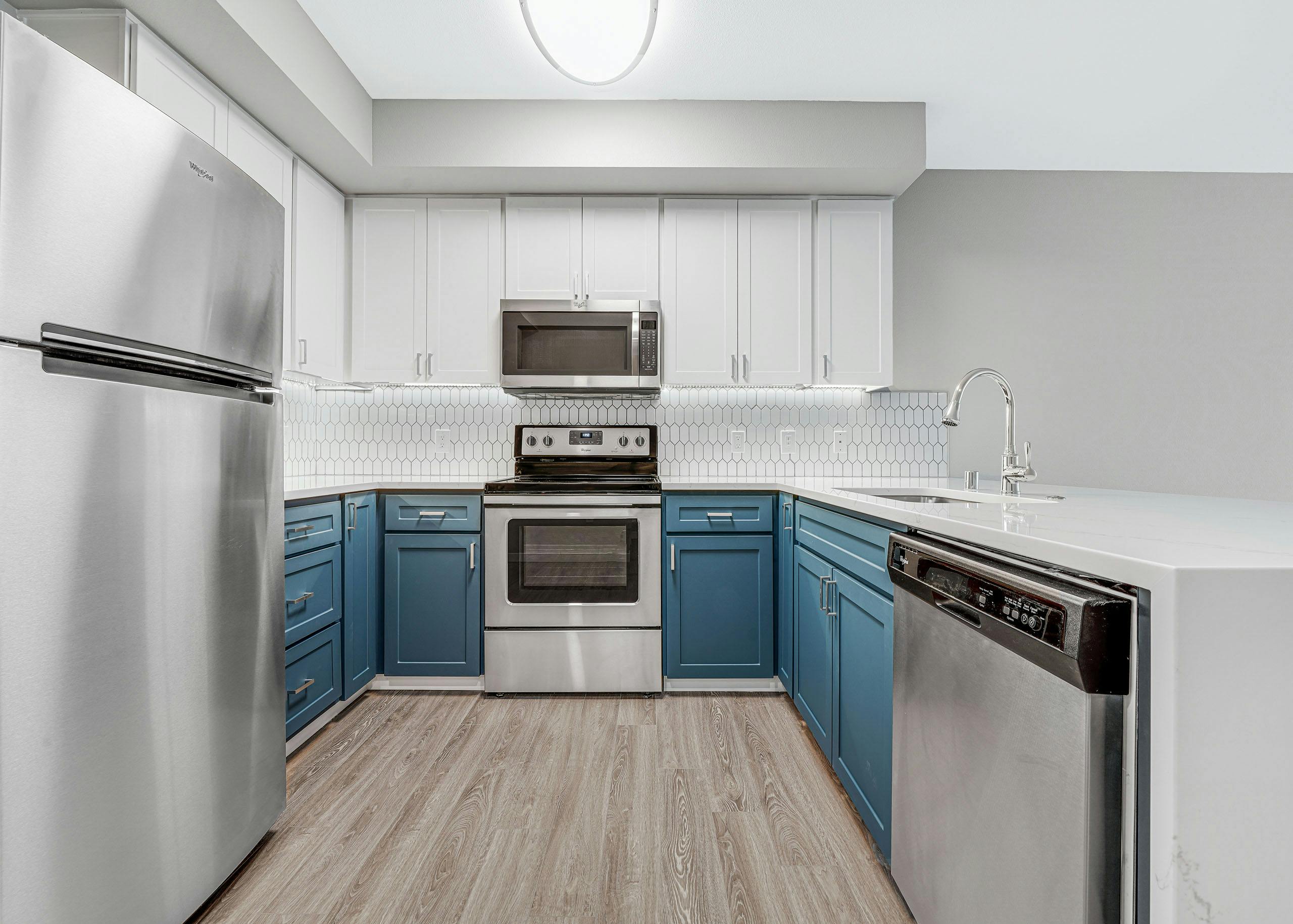 Kitchen at AMLI 535 apartment building with white and blue cabinets and stainless steel appliances with light gray floors