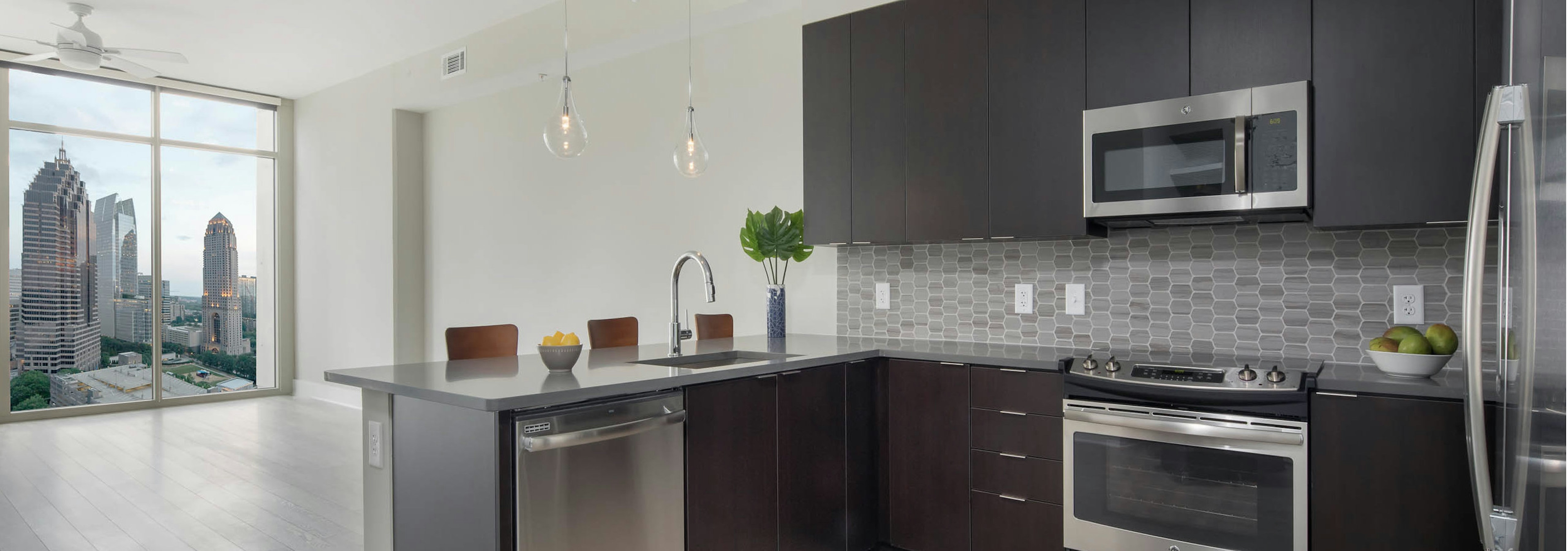 Kitchen at AMLI Arts Center with light wood floor leading to living area with floor to ceiling windows with bright city view