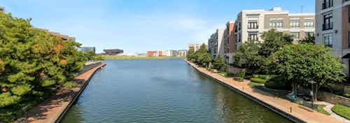 Daytime view of Lake Carolyn from AMLI Las Colinas apartments showcasing lake trail and surrounding buildings in the distance