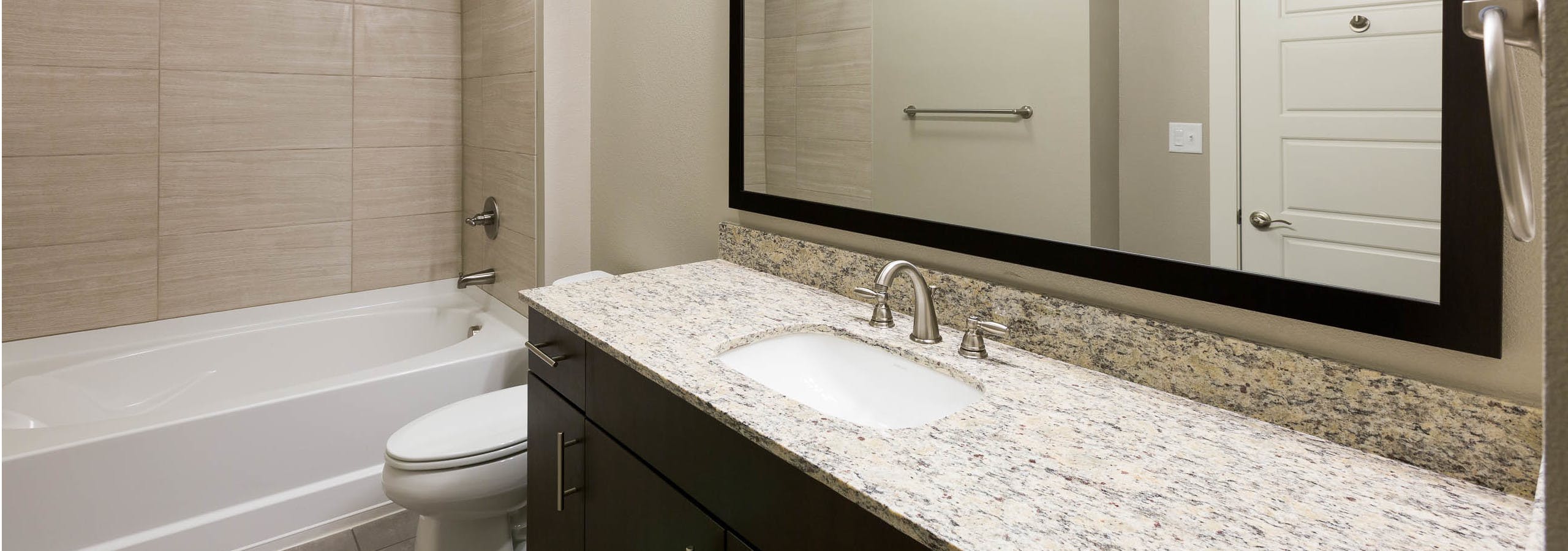 AMLI Covered Bridge bathroom with elegant granite countertop and white oversized bath tub with tile surround