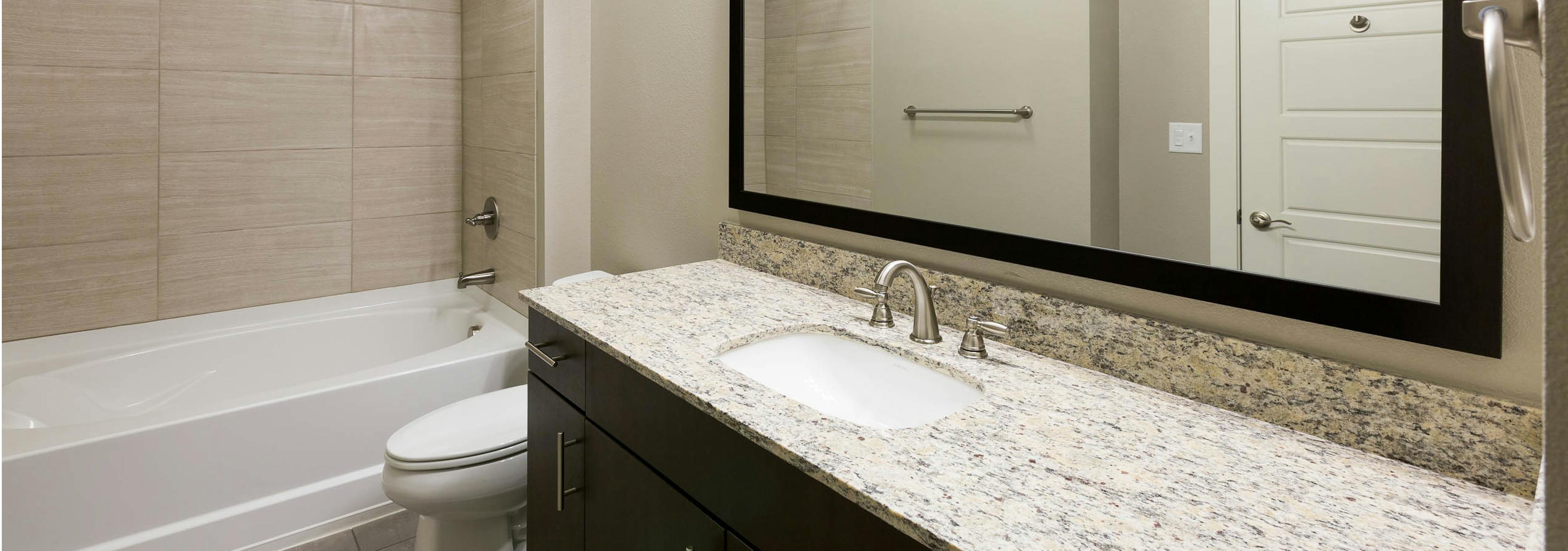 AMLI Covered Bridge bathroom with elegant granite countertop and white oversized bath tub with  tile surround