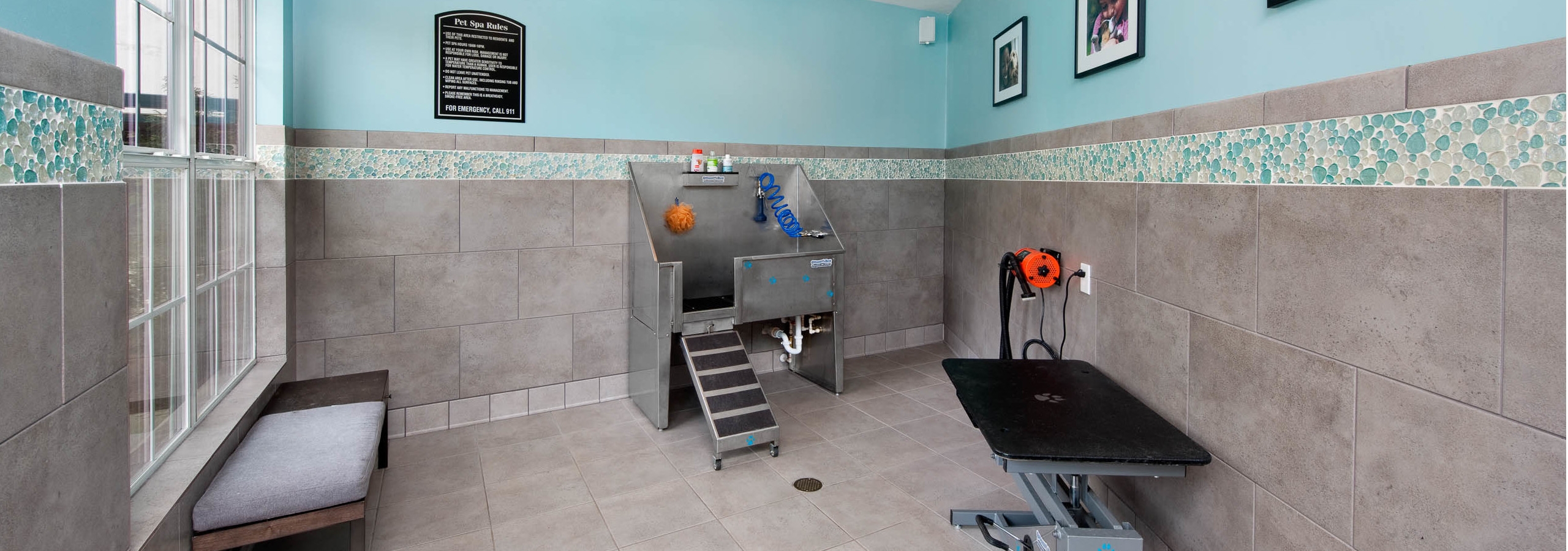 AMLI North Point paw wash with grey tiled flooring which goes onto the lower half of the walls with a deep sink and pet table