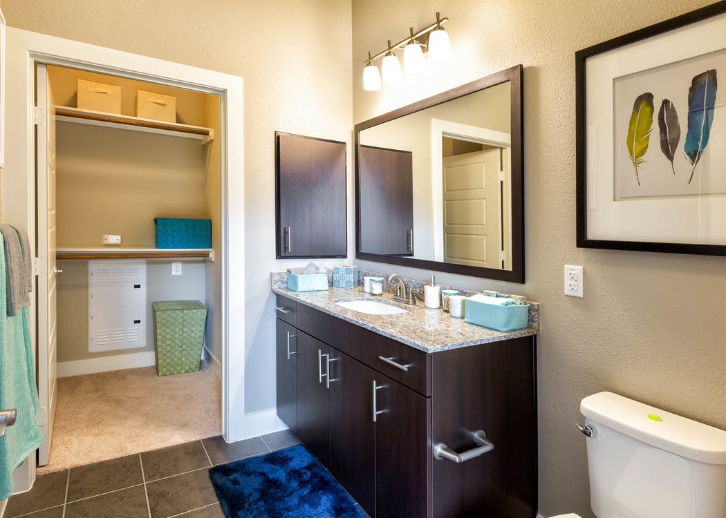 Bathroom at AMLI at Mueller featuring a black vanity sink with a light countertop and framed mirror on beige walls