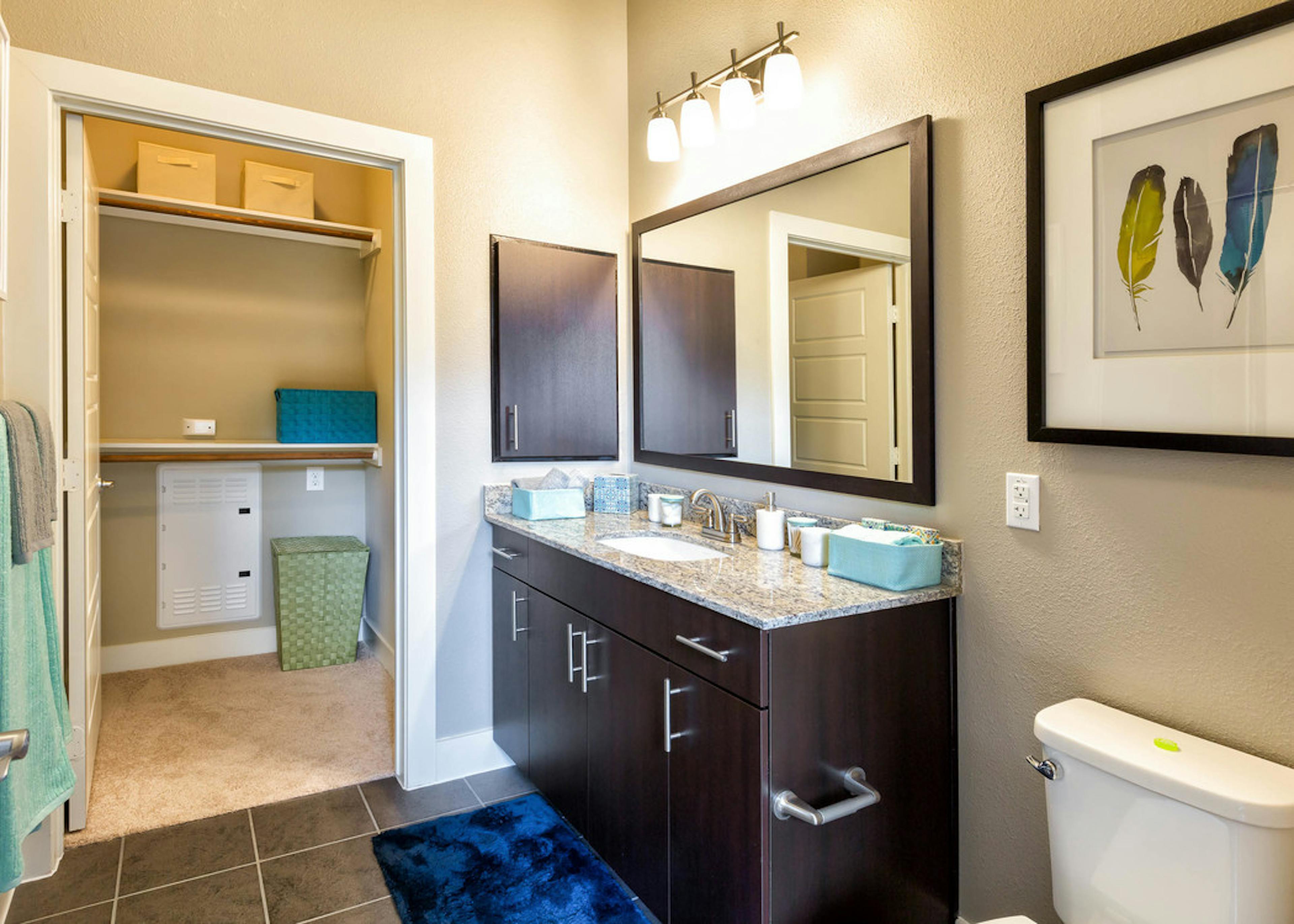 Bathroom at AMLI at Mueller featuring a black vanity sink with a light countertop and framed mirror on beige walls