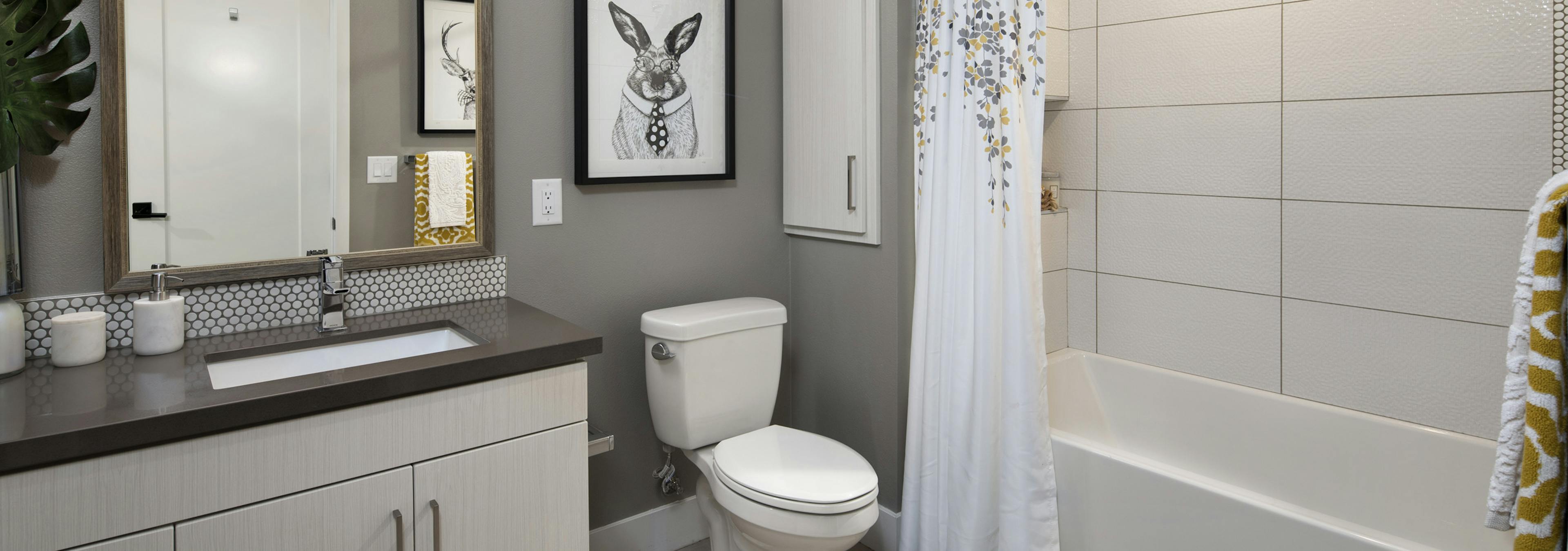 Interior of AMLI Marina Del Rey apartment bathroom with grey quartz countertop and soaking tub, tile surround and soap niche