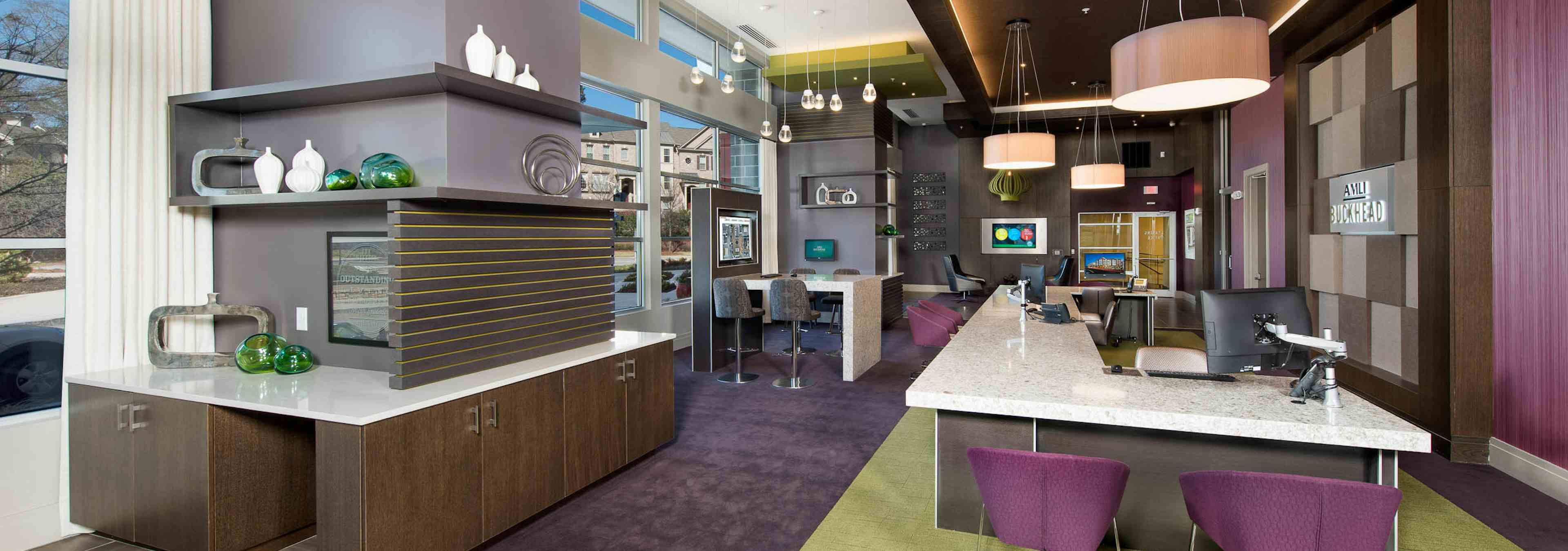 AMLI Buckhead leasing office with a long white desk with computers and purple office chairs with dark carpeted floors