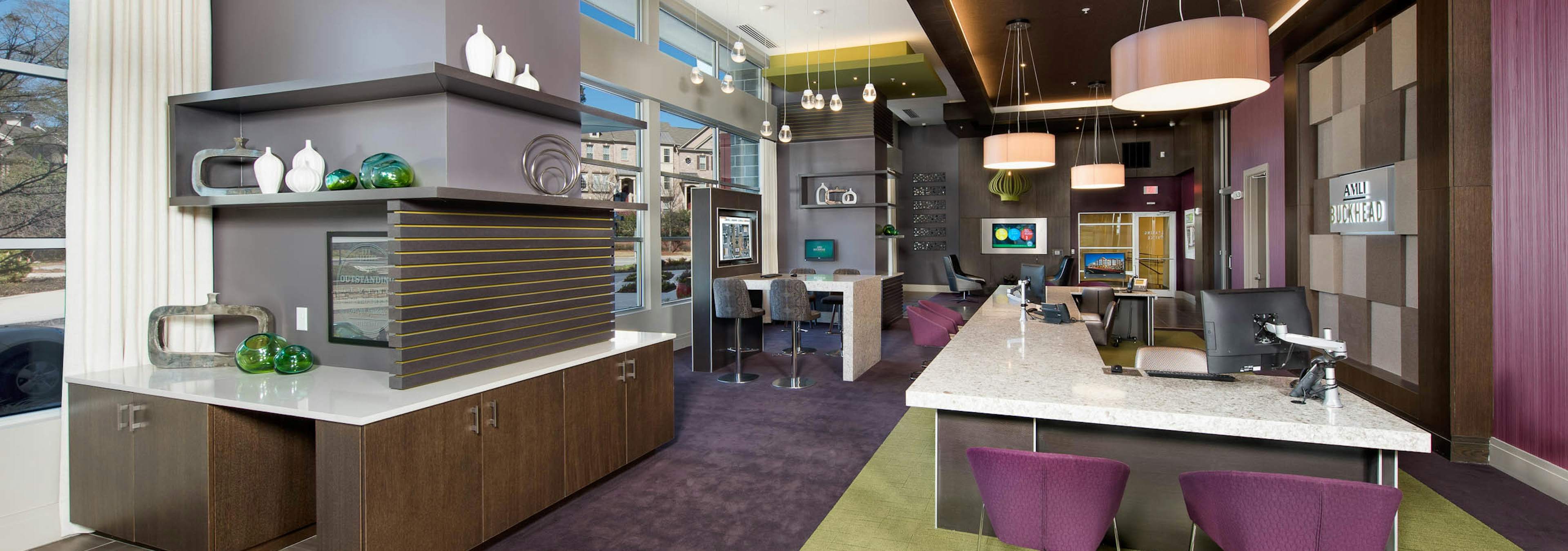 AMLI Buckhead leasing office with a long white desk with computers and purple office chairs with dark carpeted floors