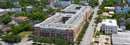 Exterior daytime aerial view of AMLI River Oaks apartment building brick facade in Houston’s Hyde Park neighborhood