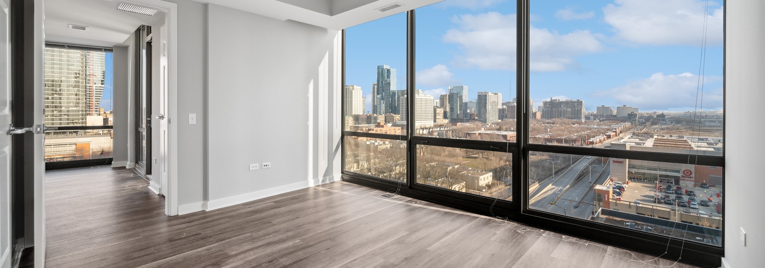 Empty bedroom with brown wood floors and a wall of floor to ceiling windows overlooking the city at AMLI 900 apartments