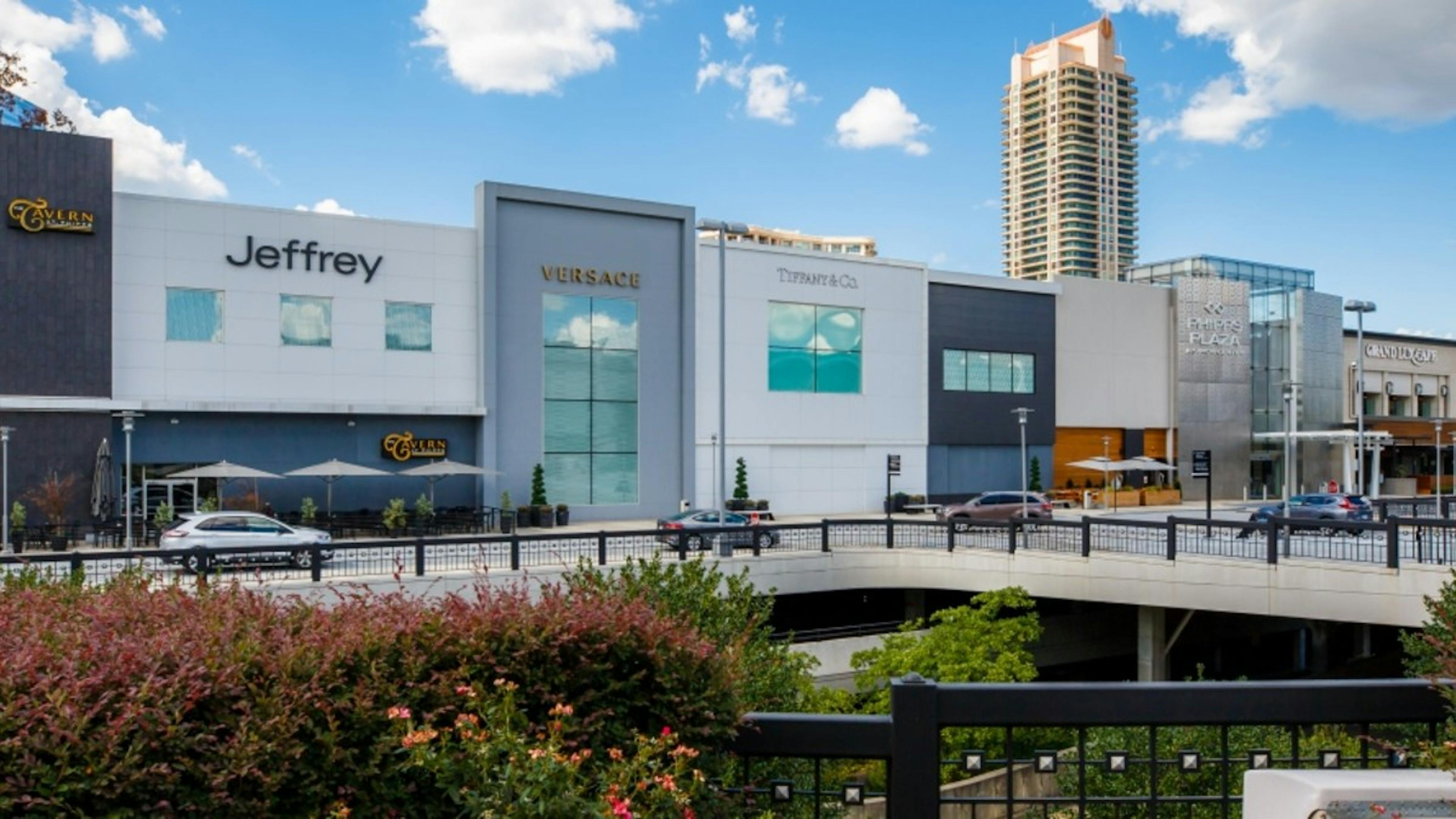 A nearby mall called Phipps Plaza showing storefronts of differing facade with a cloudy blue sky in the background