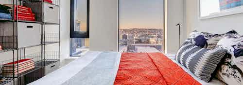 Interior view of apartment of AMLI Arc bedroom with white walls large window with view and space for a queen bed
