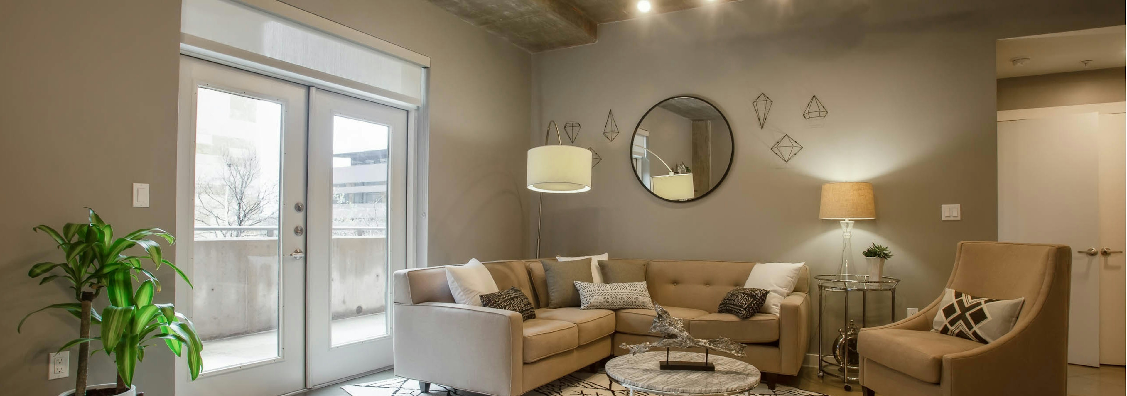 Interior of AMLI Downtown living room with neutral colored seating in front of balcony doors with bright daytime view