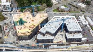 Aerial view of AMLI Redmond Way site with two blue cranes rising above two buildings under construction