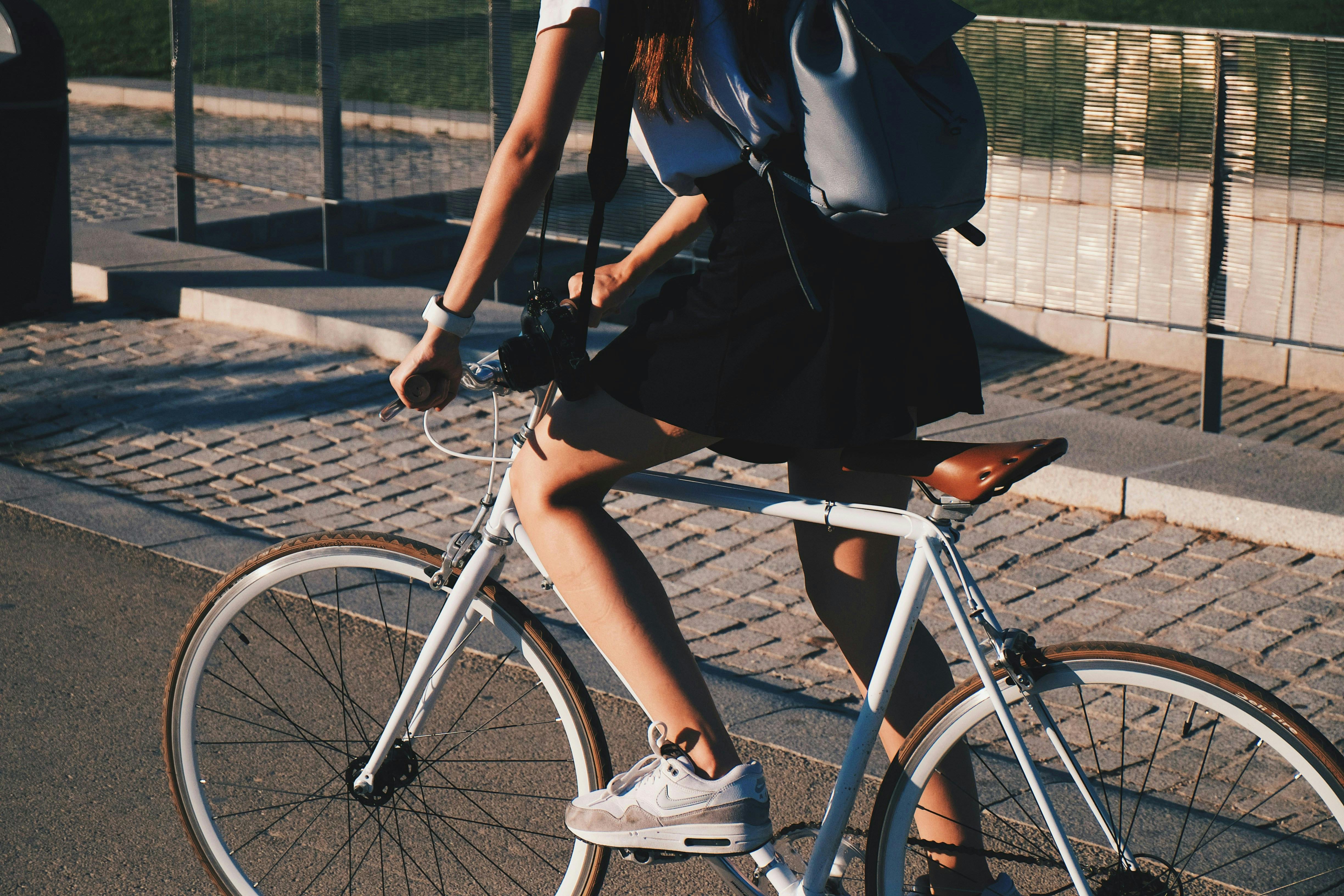 A woman with a backpack riding a pretty leather seated bike