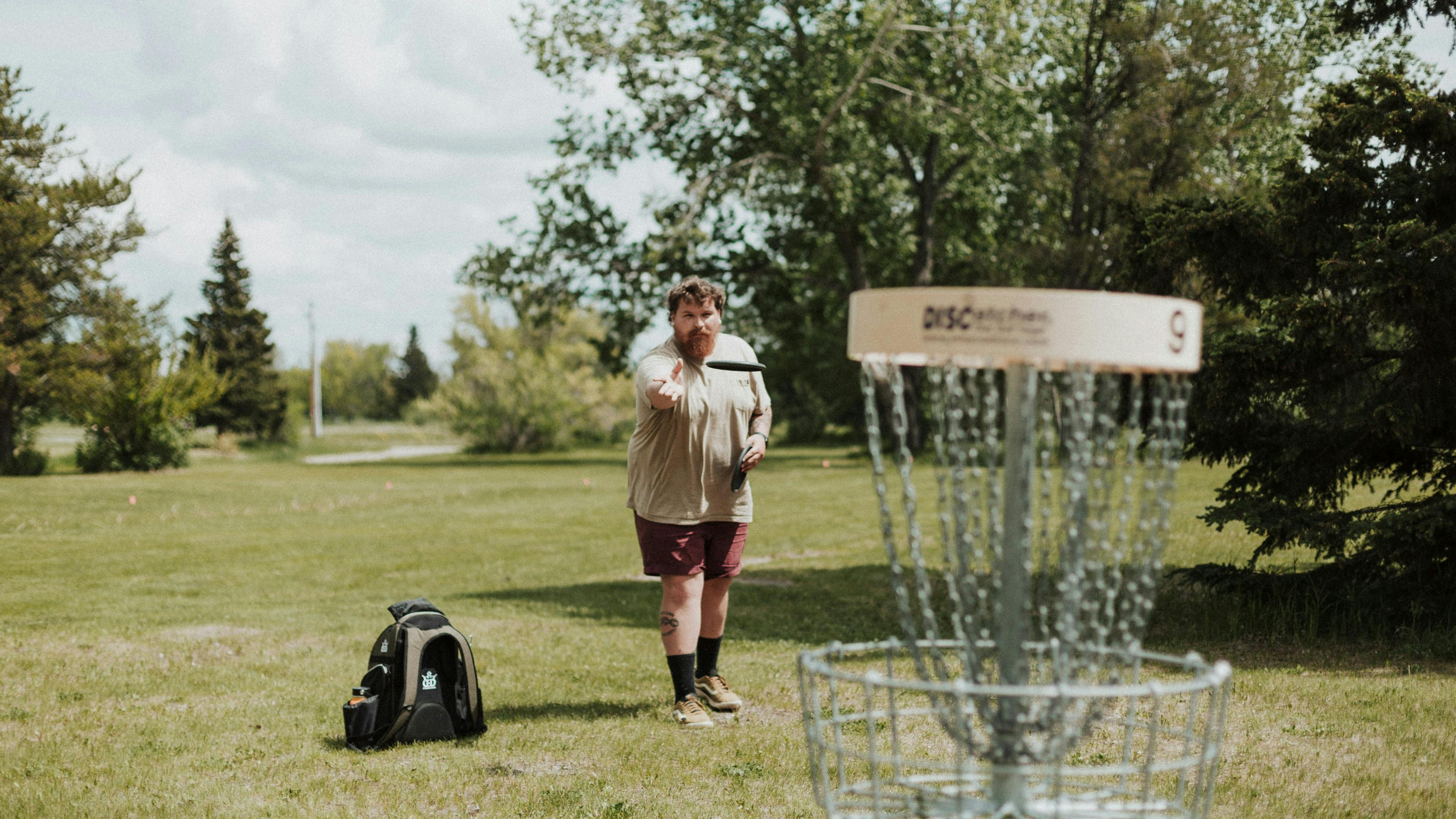 A disc golfer throwing a putt into a disc golf basket