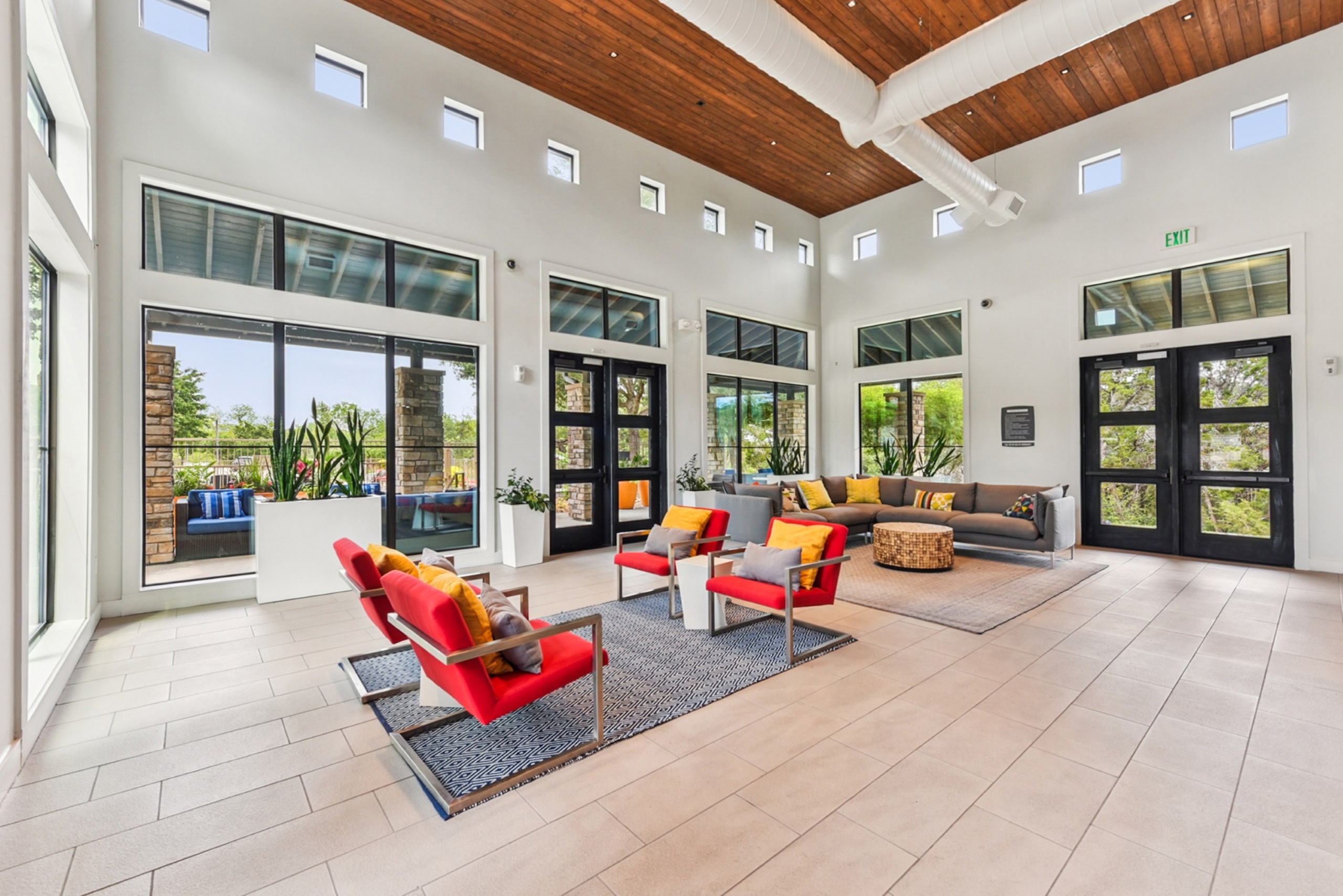 Spacious clubhouse at AMLI Covered Bridge apartments with large windows, bright furniture and light tile floor