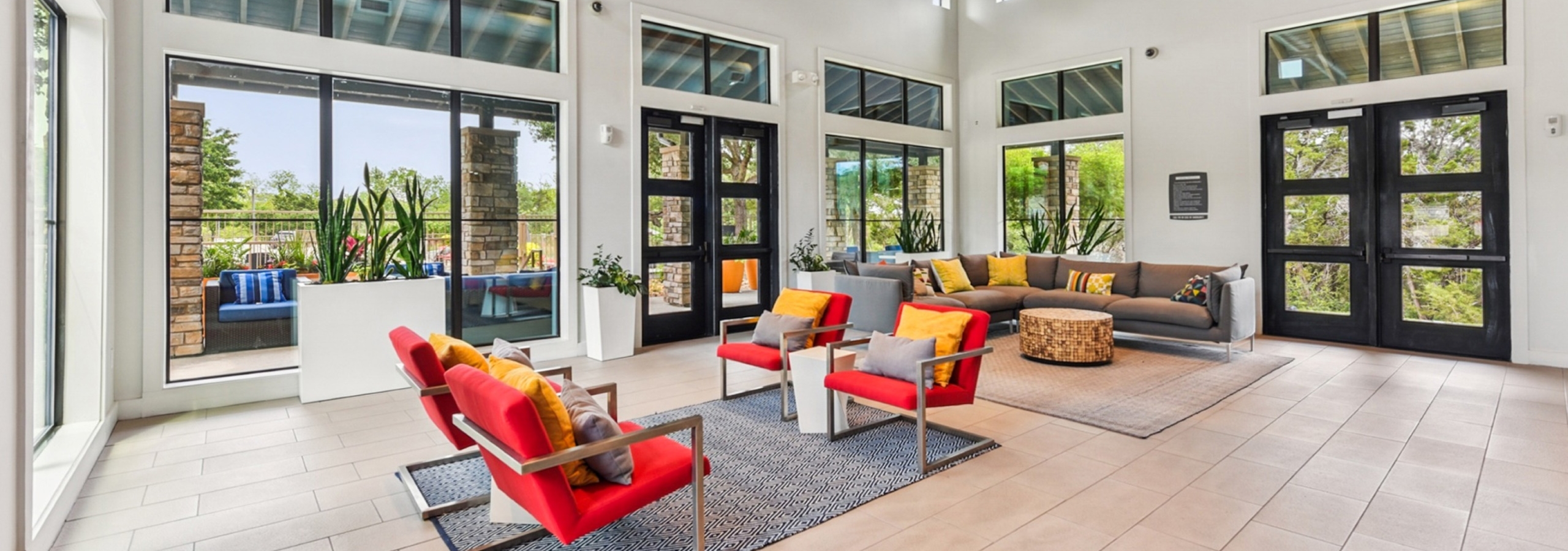 Spacious clubhouse at AMLI Covered Bridge apartments with large windows, bright furniture and light tile floor