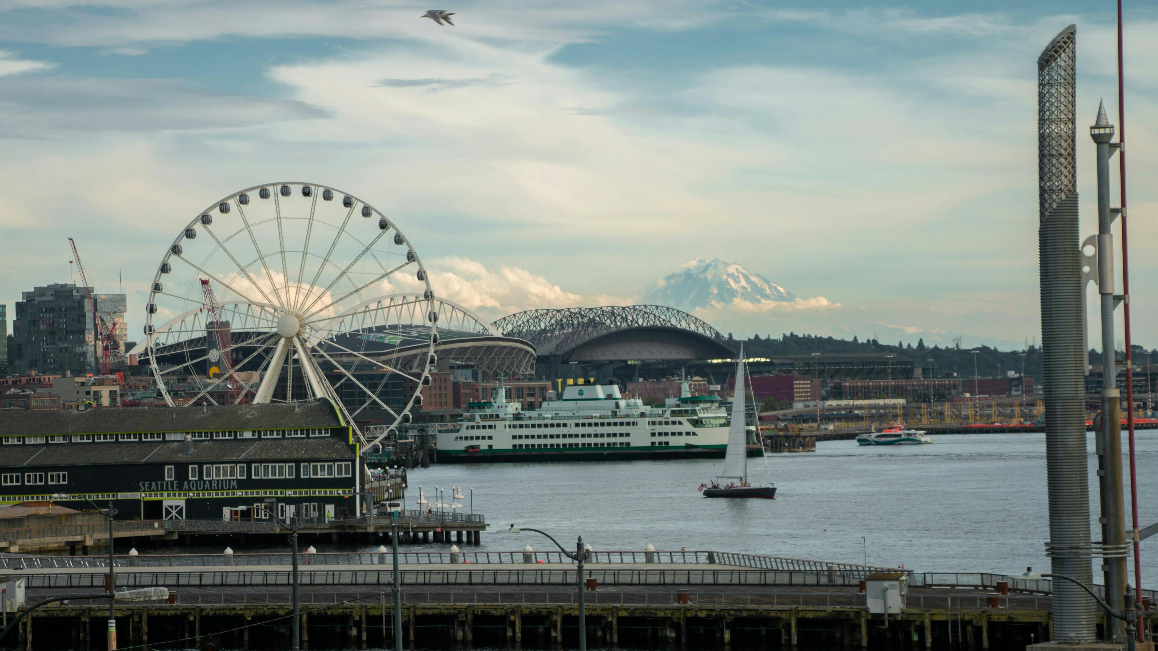 A ferris wheel and a sailboat seen with Mount Rainier in the background