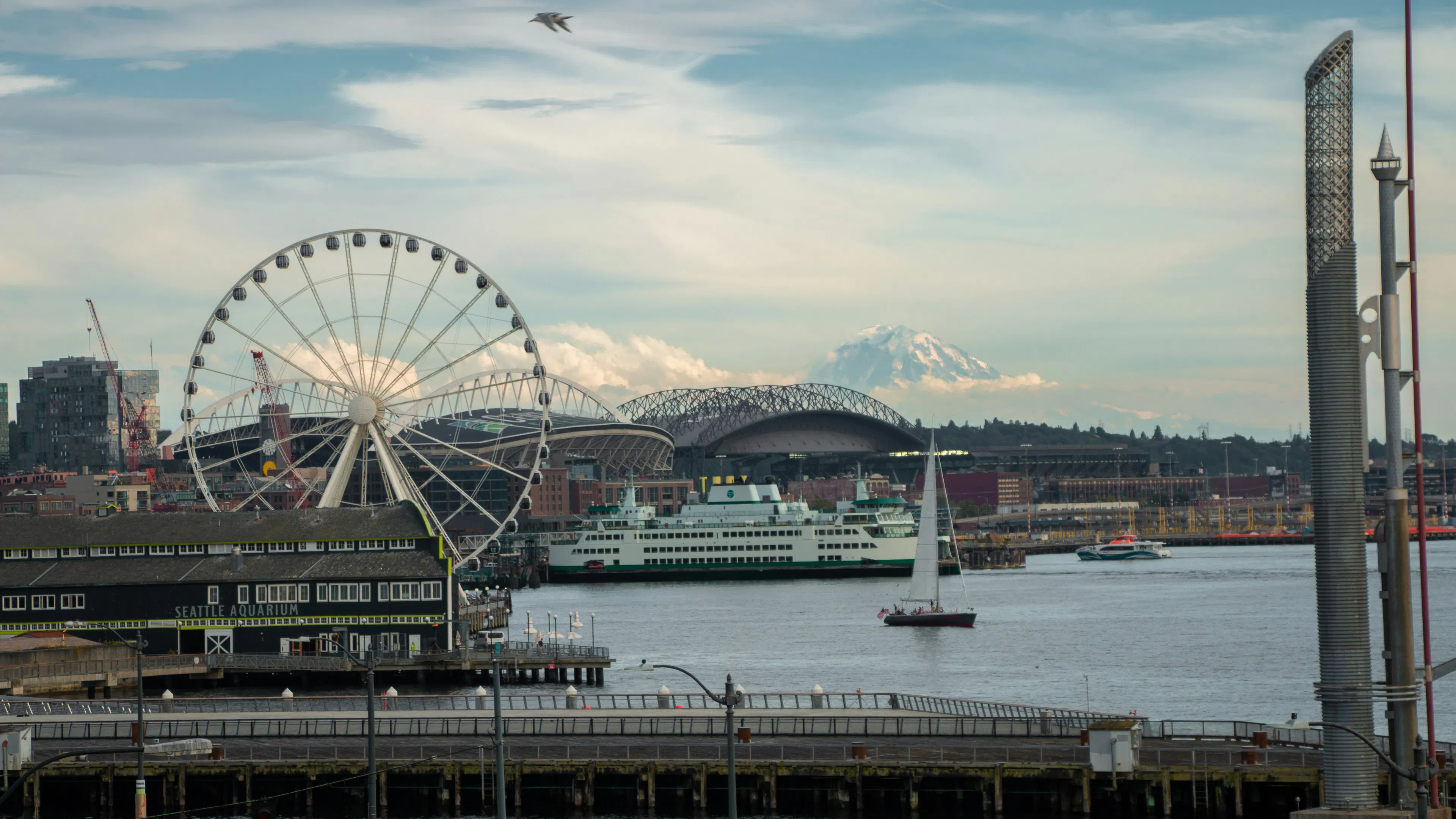 A ferris wheel and a sailboat seen with Mount Rainier in the background