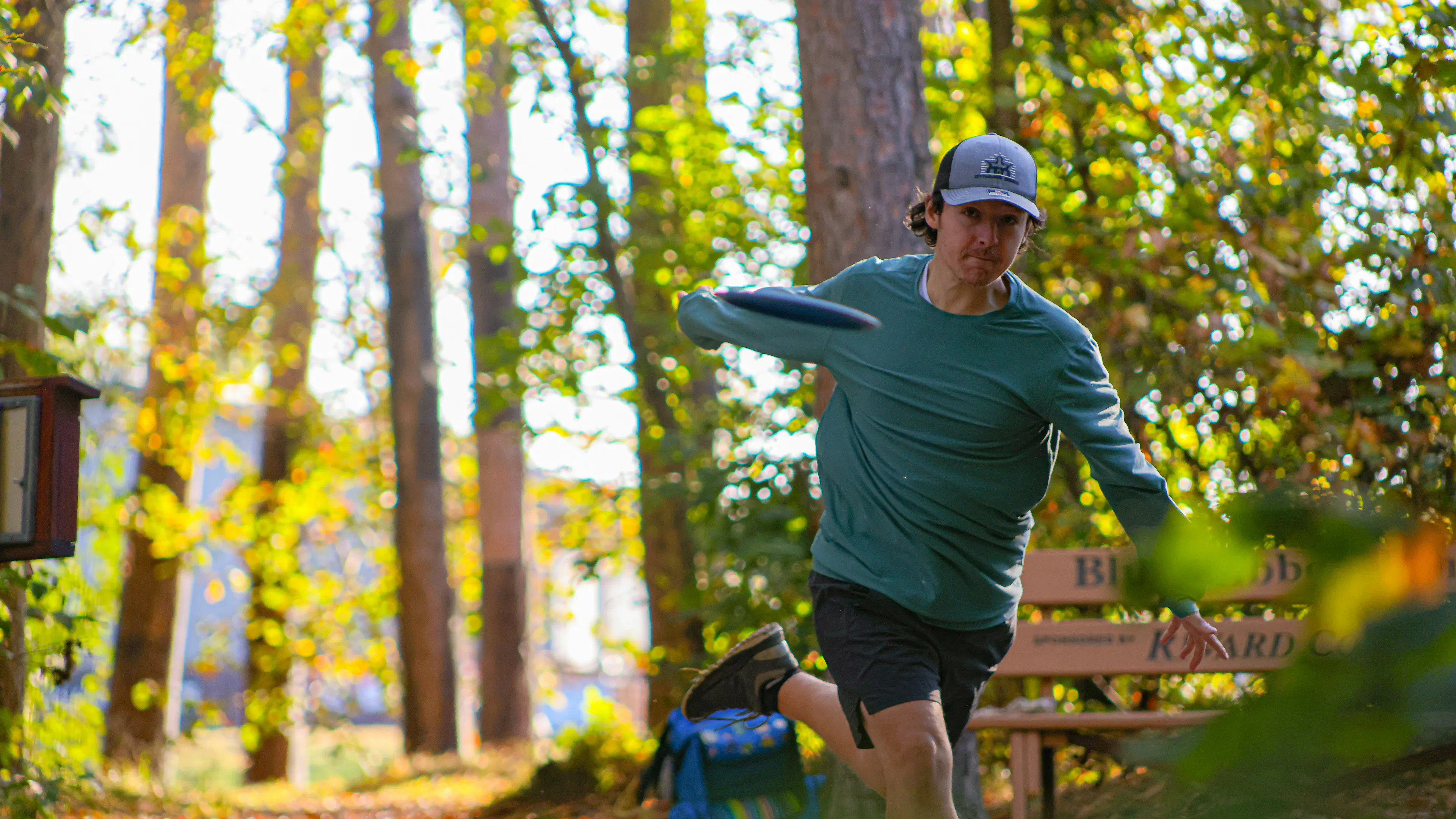 A man in a green shirt throwing a disc on a disc golf course