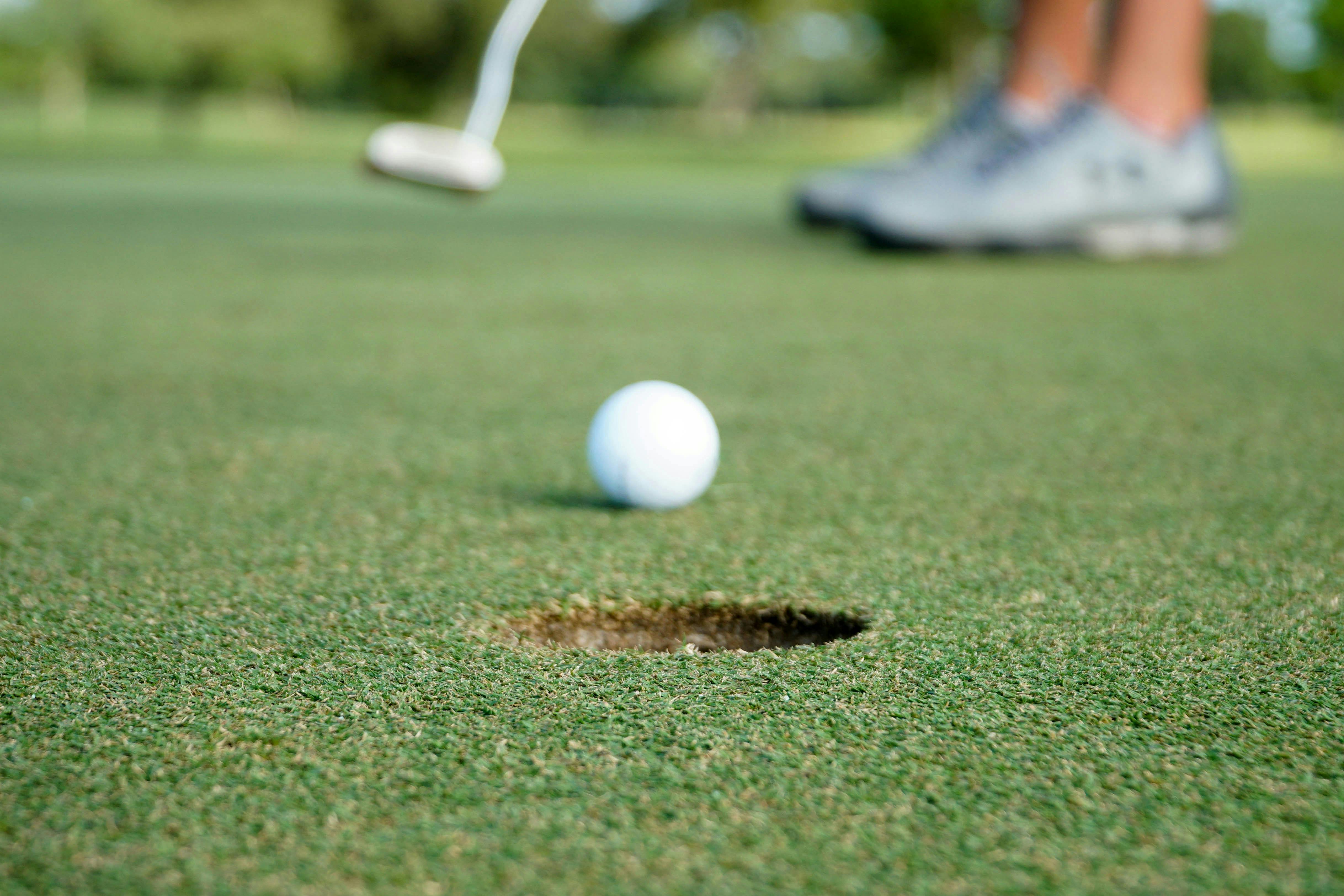 A golf ball heading toward a hole on a putting green 