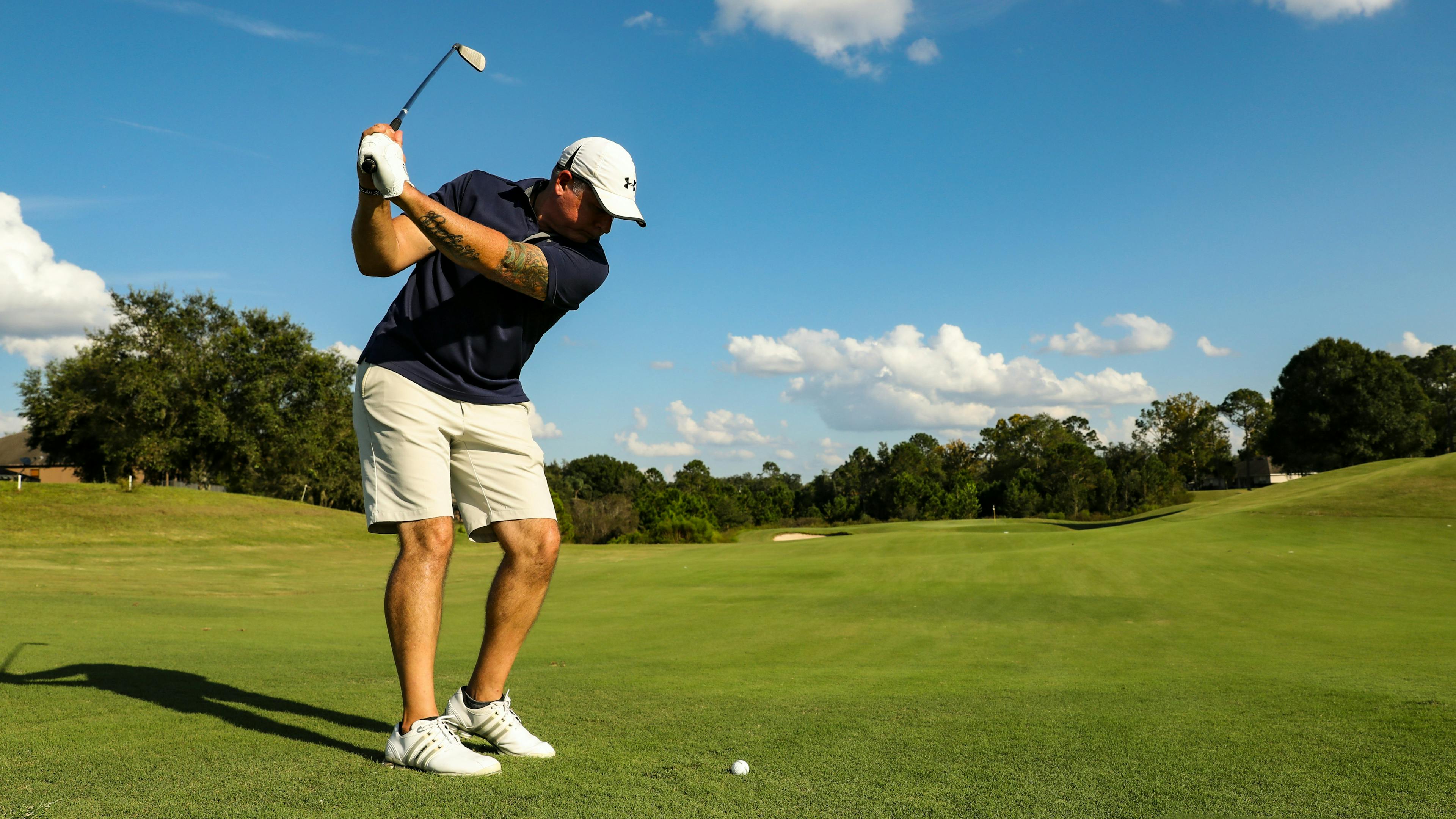 A golfer in a black shirt setting up for a swing on a tee