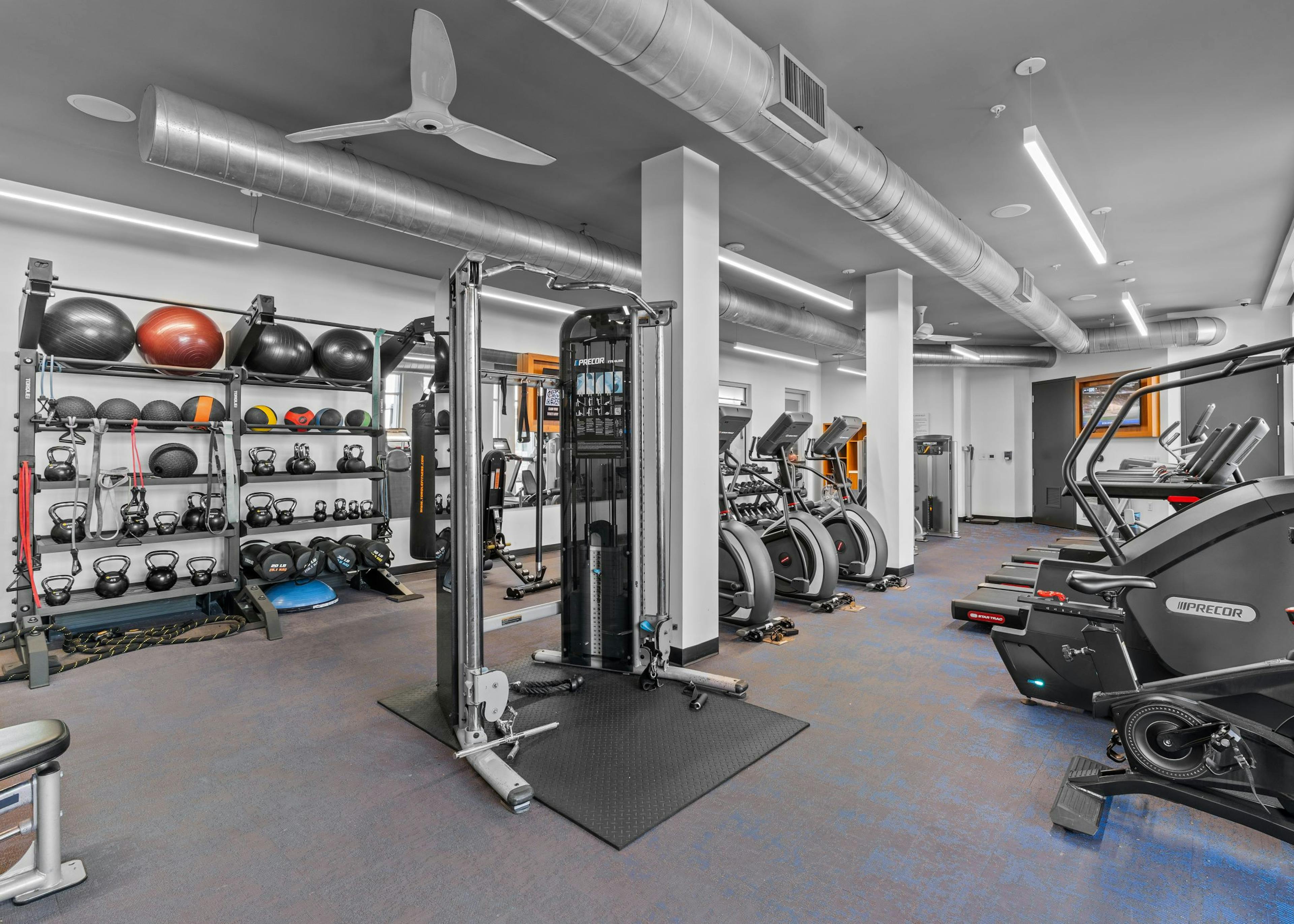 Interior of fitness center at AMLI Uptown Orange apartments with cardio machines, free weights and medicine balls