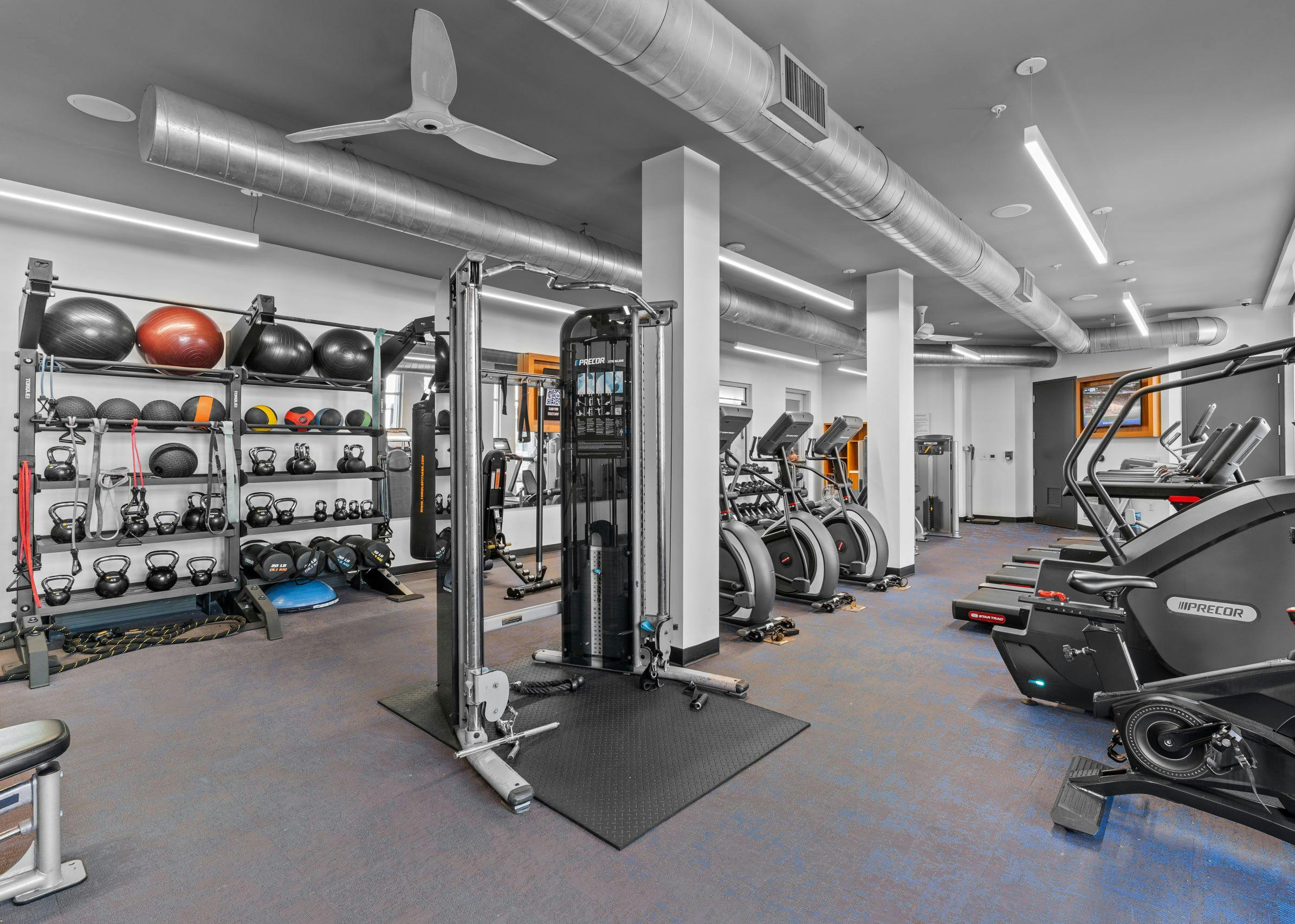 Interior of fitness center at AMLI Uptown Orange apartments with cardio machines, free weights and medicine balls