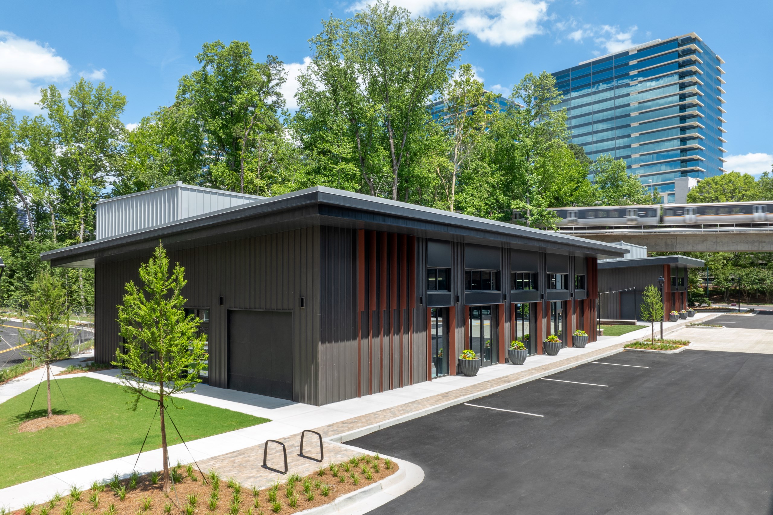 Retail village brown building with garage doors below train tracks at AMLI Brookhaven apartment community