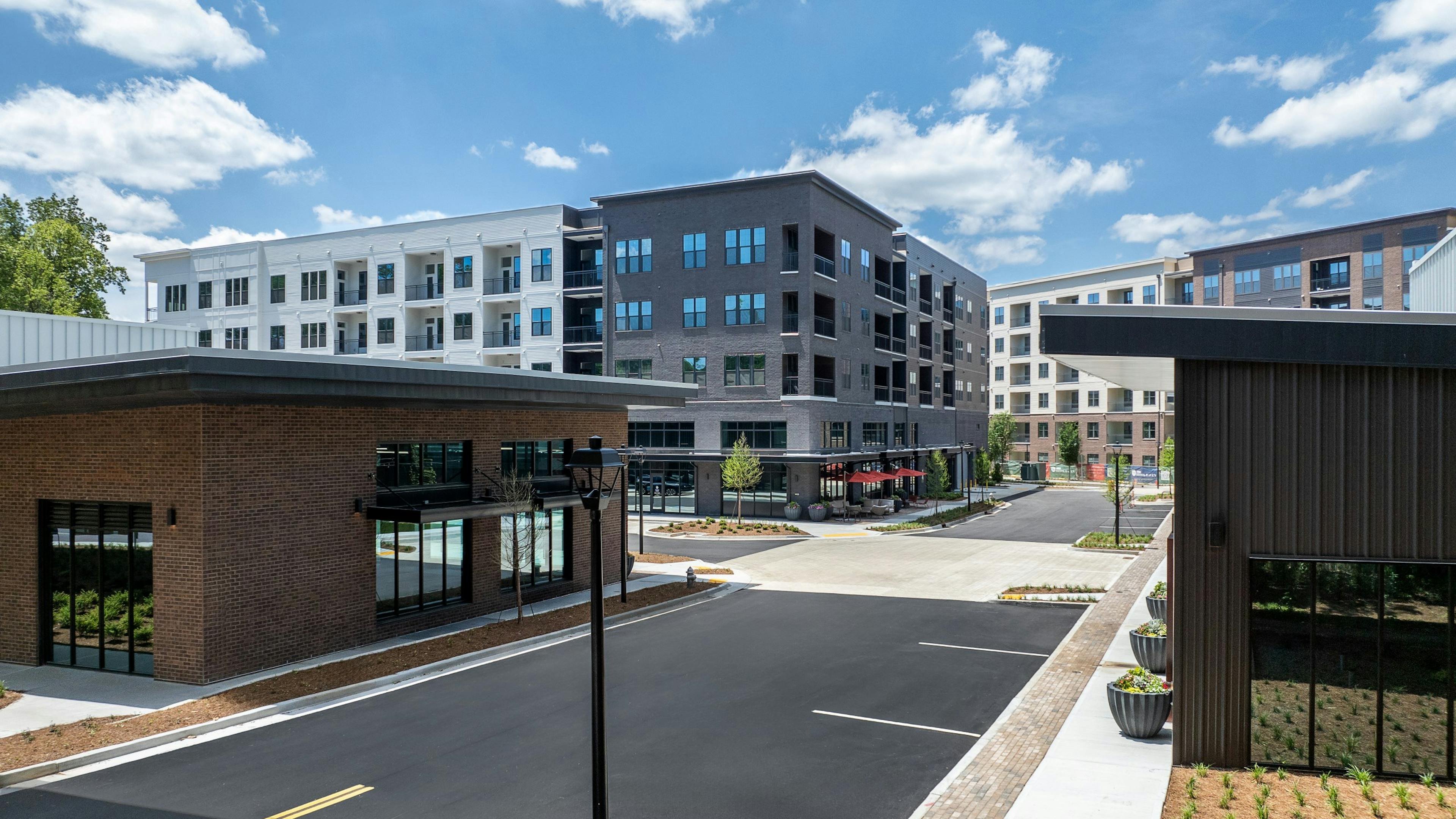 AMLI Brookhaven four story apartment building with gray and white exterior and retail area with one story buildings