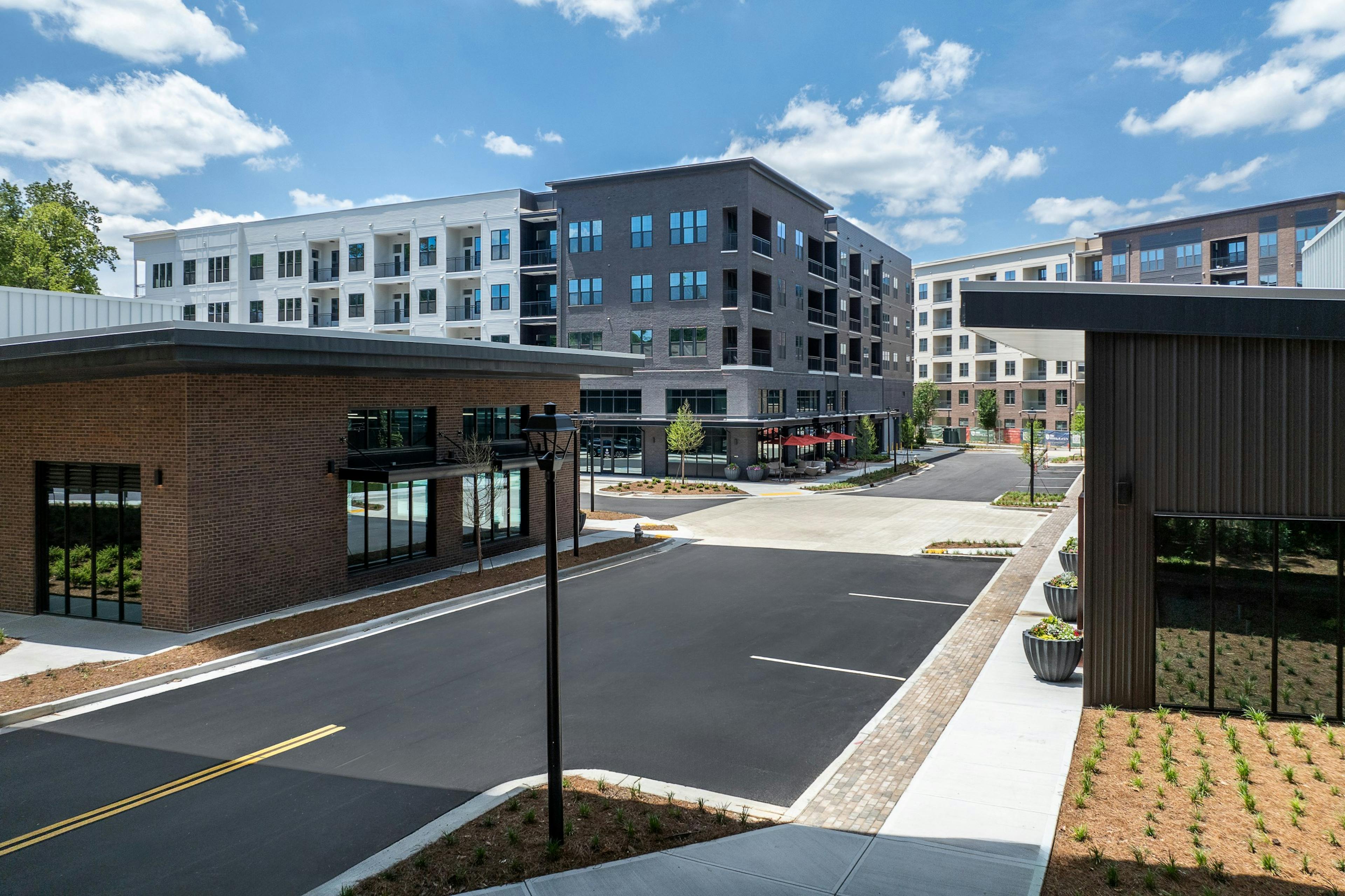 AMLI Brookhaven four story apartment building with gray and white exterior and retail area with one story buildings