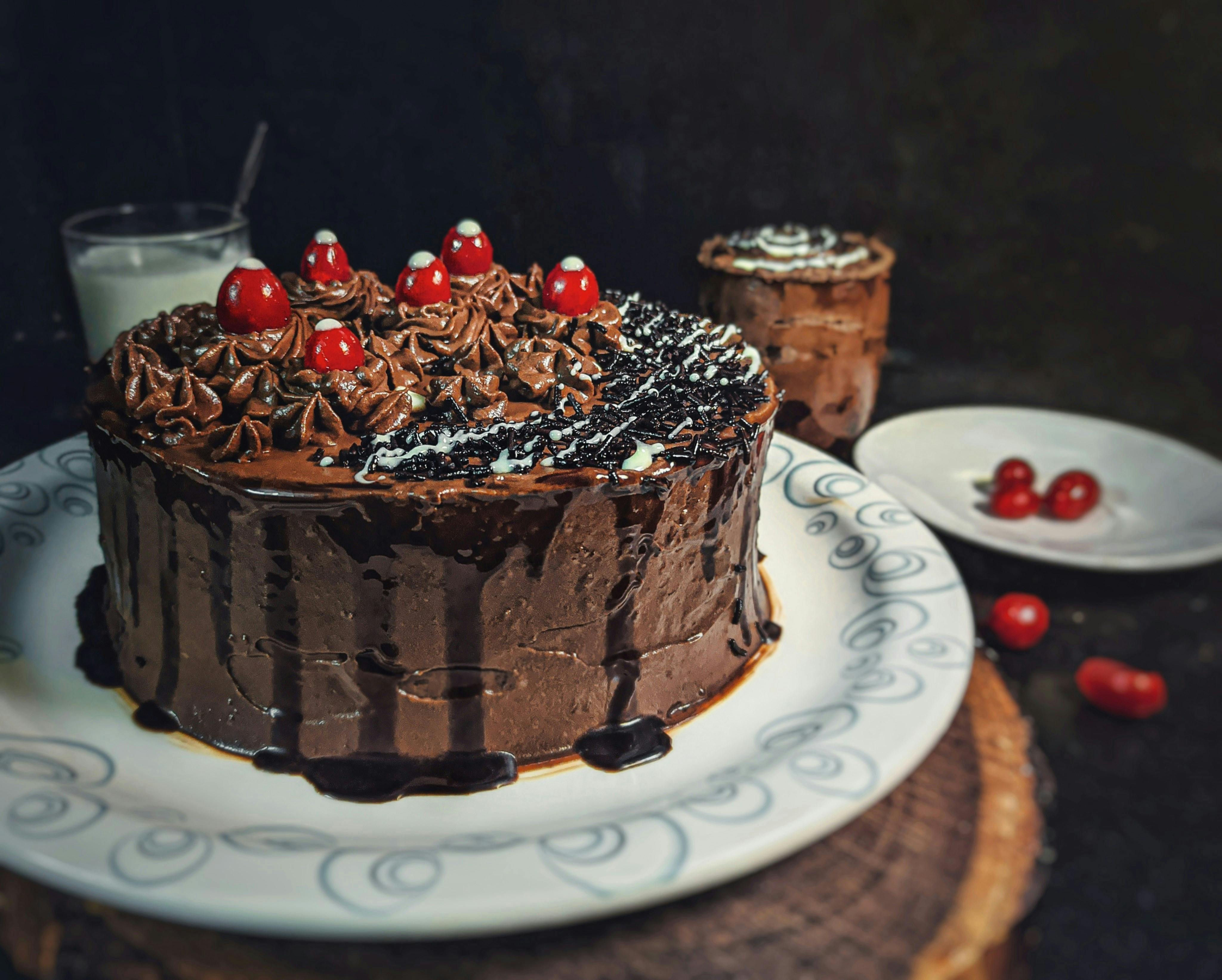 A tall black forest cake decorated with cherries and chocolate shavings 