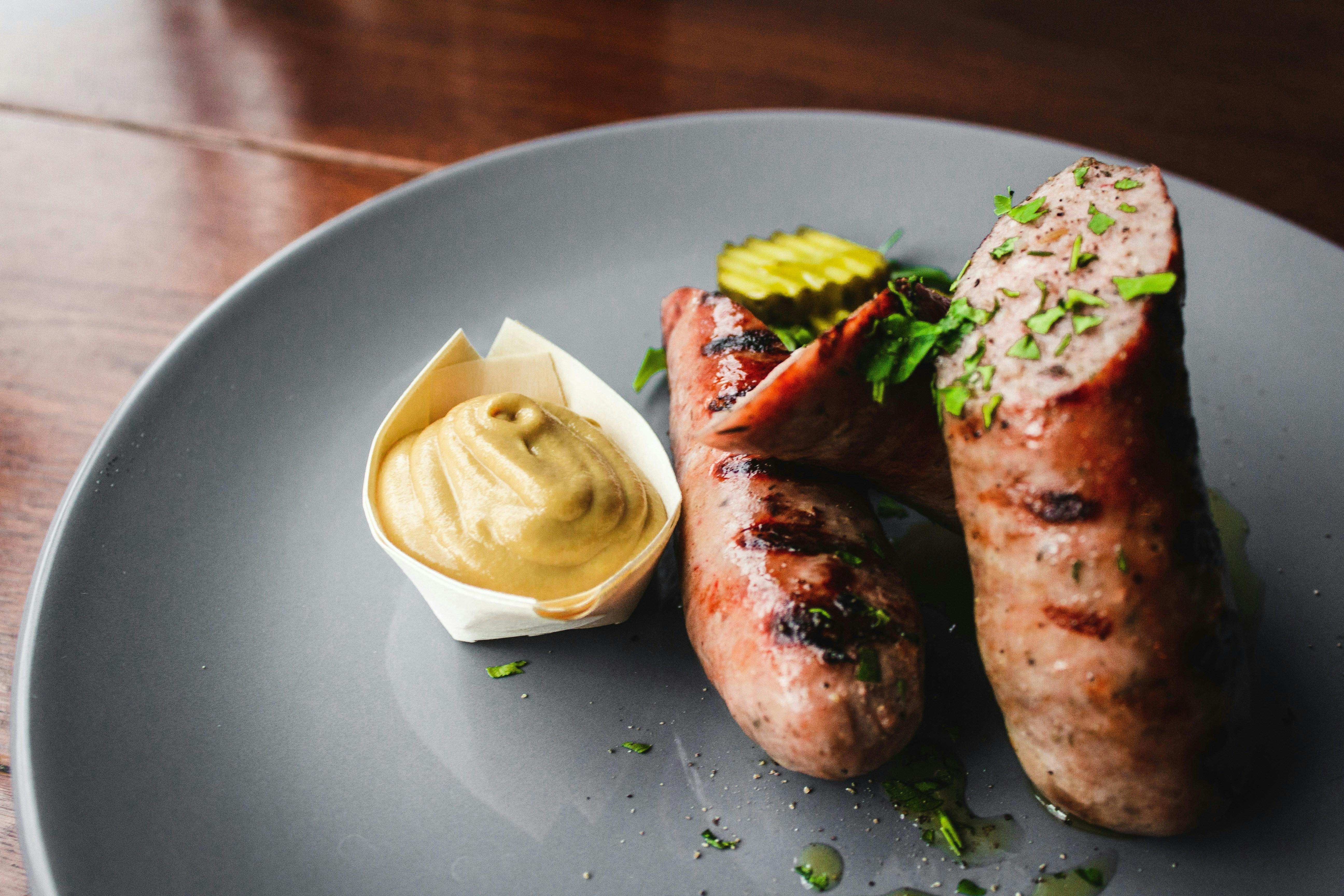 A gray plate with two pieces of bratwurst on it