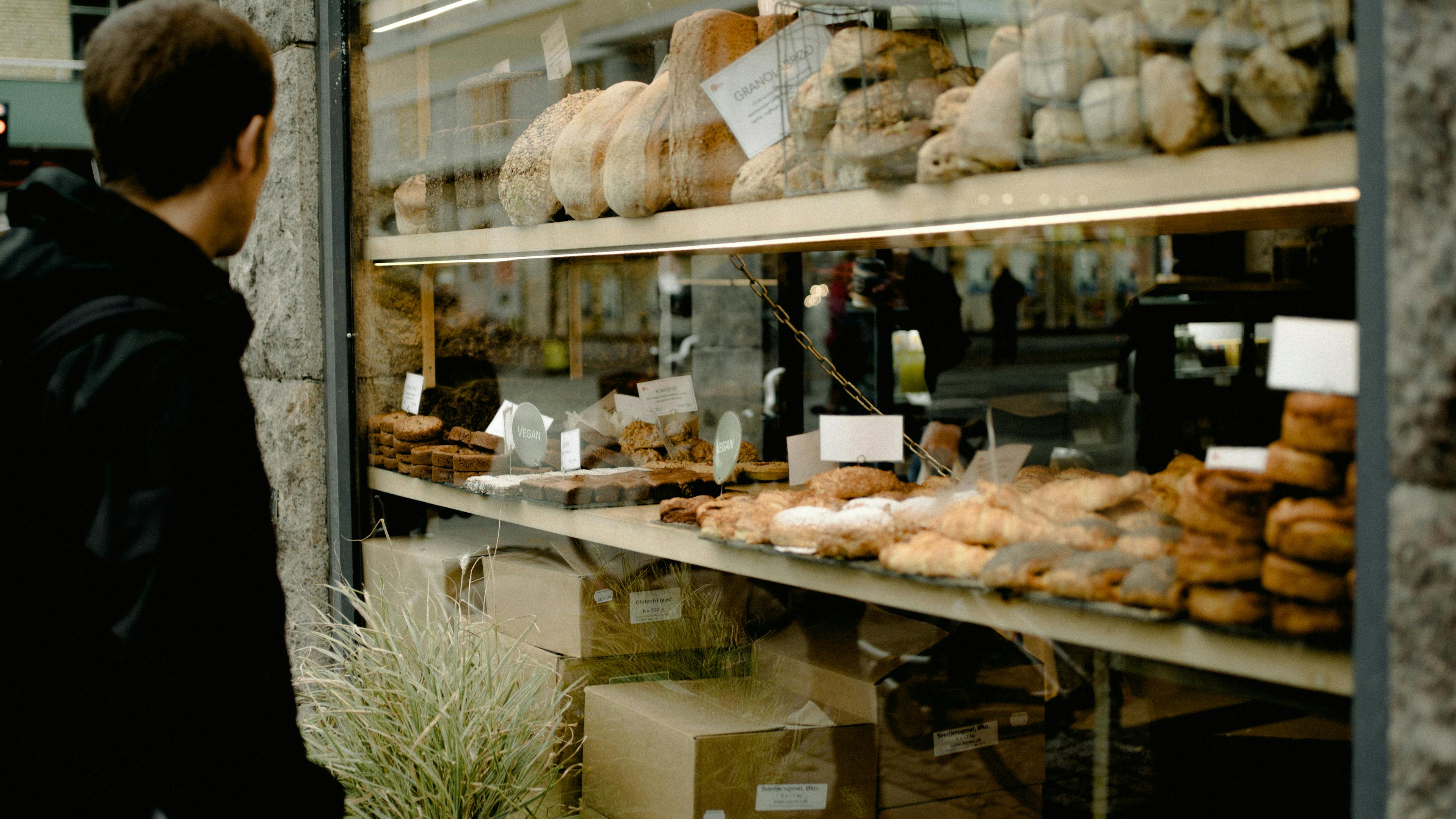 A man in a black jacket looking into a bakery window