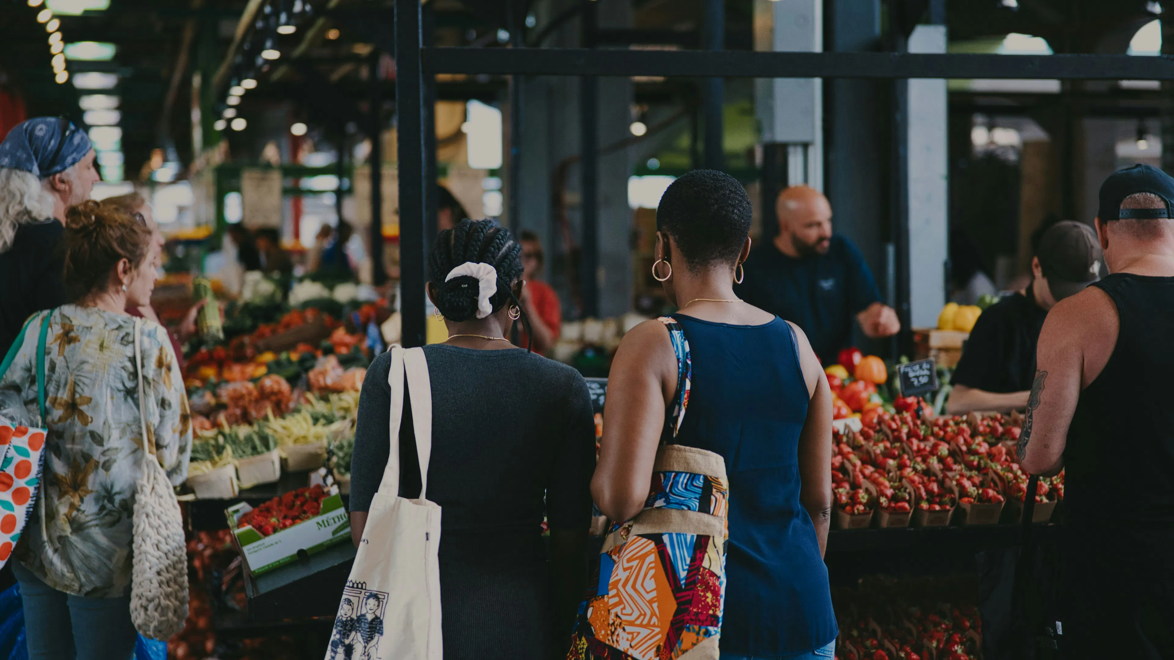 Two people at an indoors farmers market looking at produce