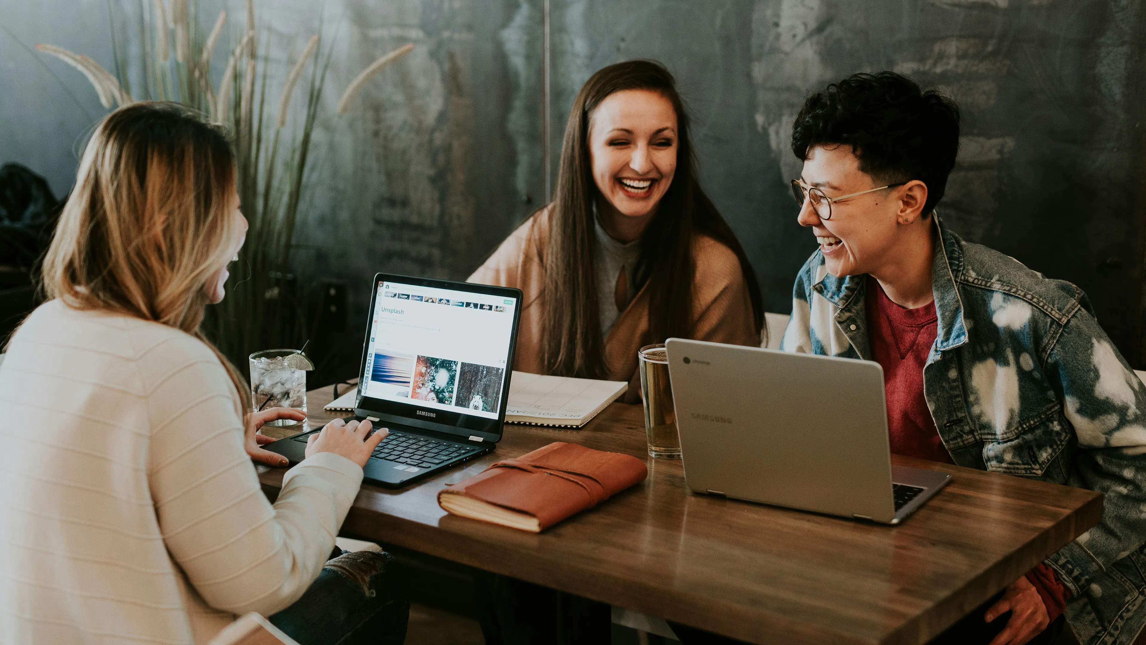 Three people sitting around a small table with laptops