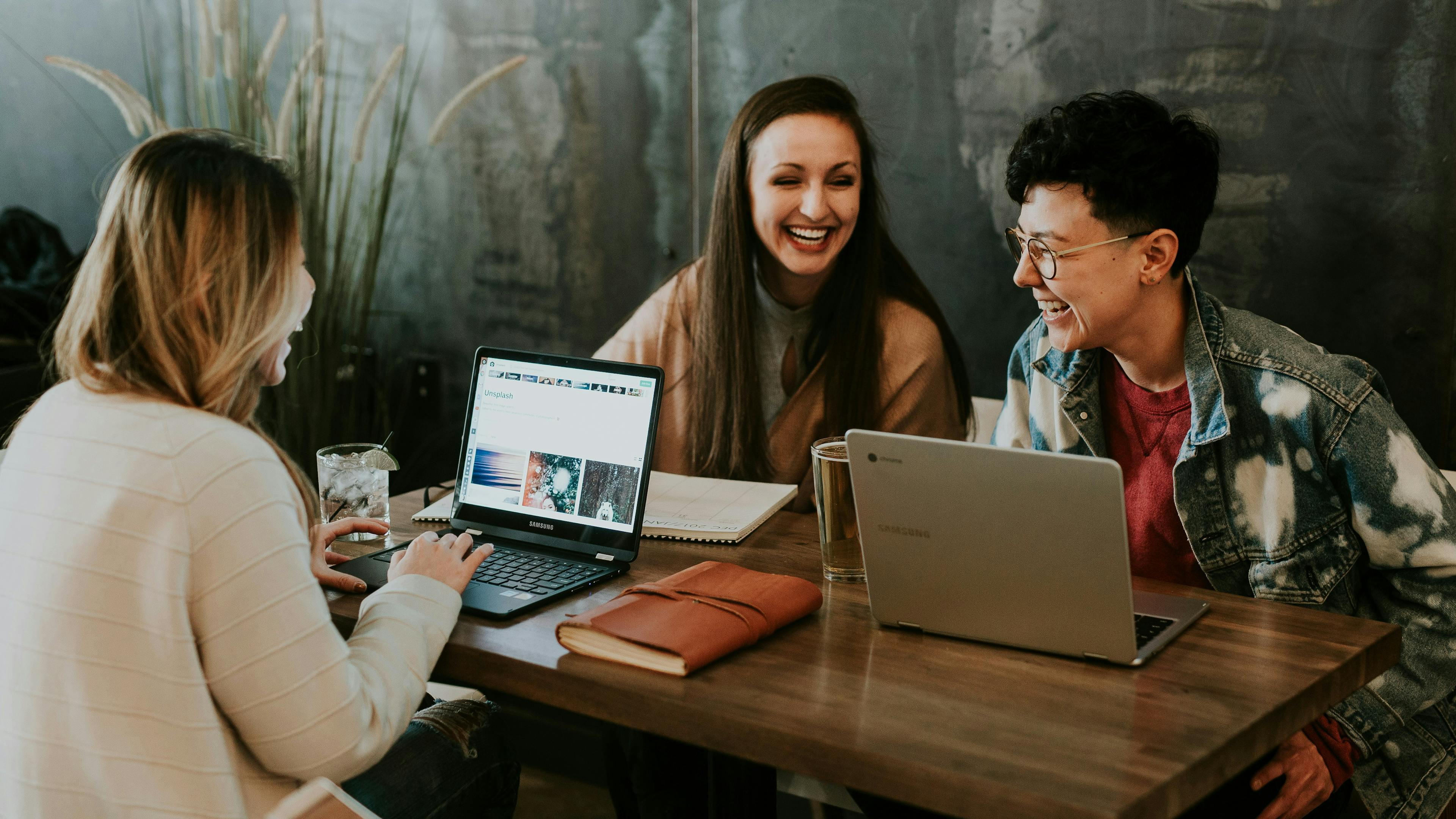 Three people sitting around a small table with laptops