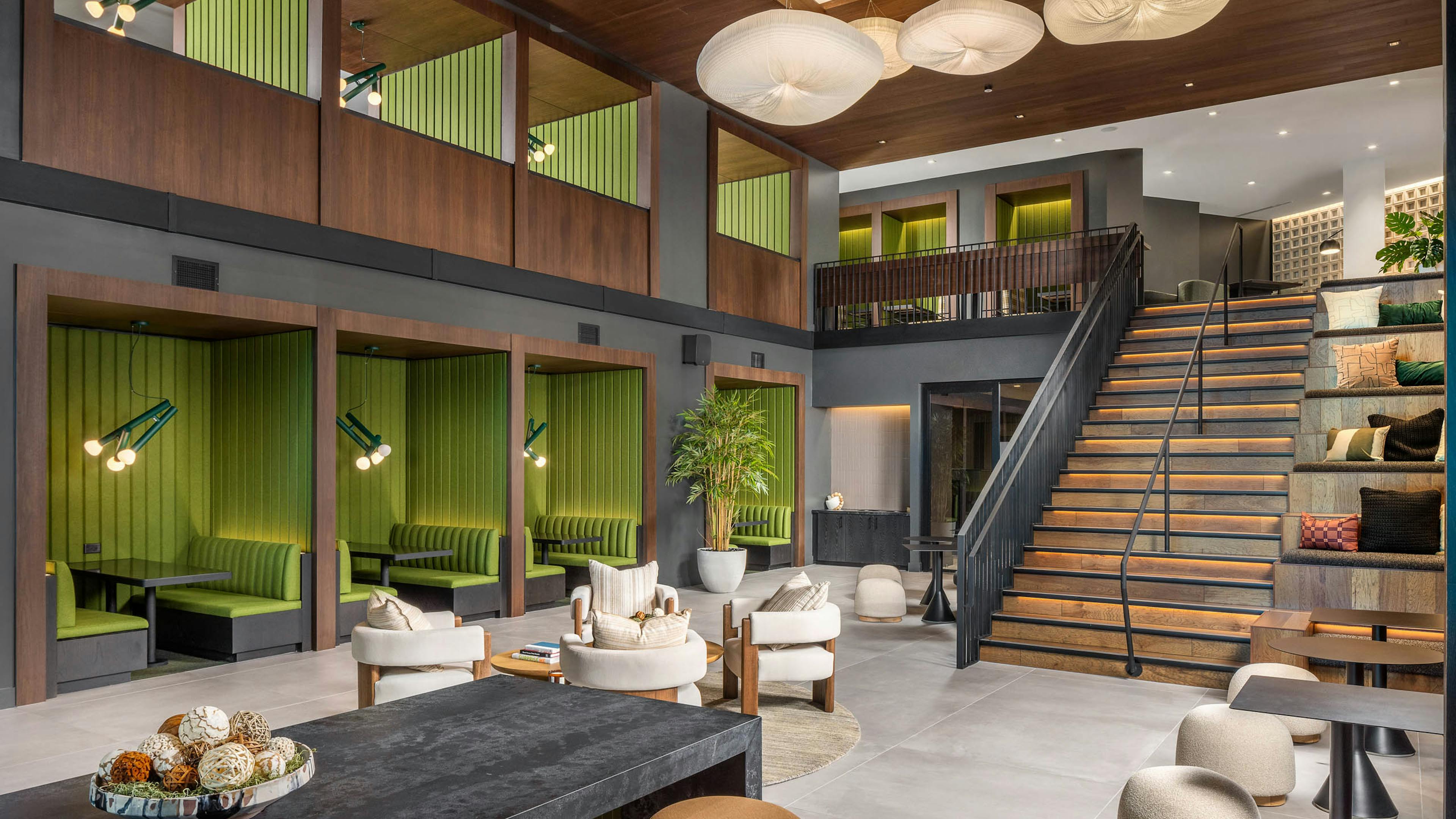 AMLI Brookhaven 2-story clubroom with plush furniture, green booths and tables under a wooden vaulted ceiling and stylish lighting