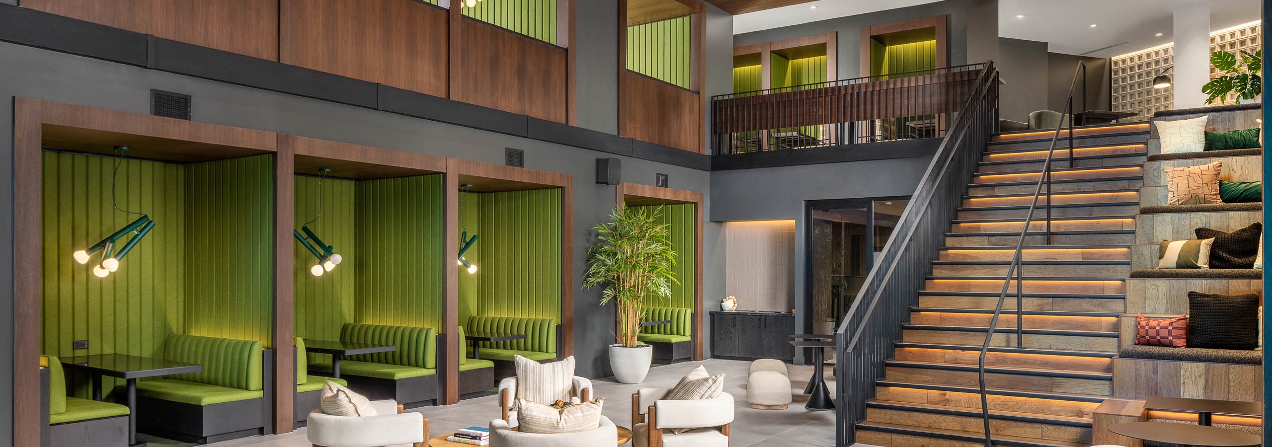 AMLI Brookhaven 2-story clubroom with plush furniture, green booths and tables under a wooden vaulted ceiling and stylish lighting