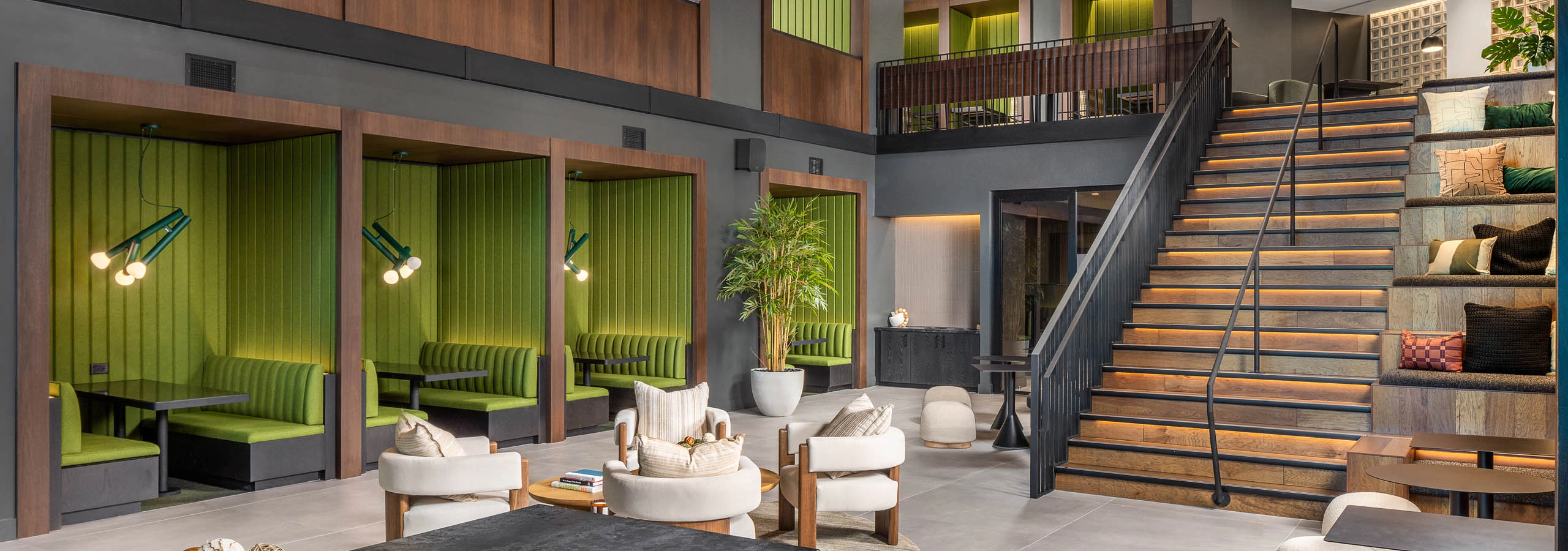 AMLI Brookhaven 2-story clubroom with plush furniture, green booths and tables under a wooden vaulted ceiling and stylish lighting