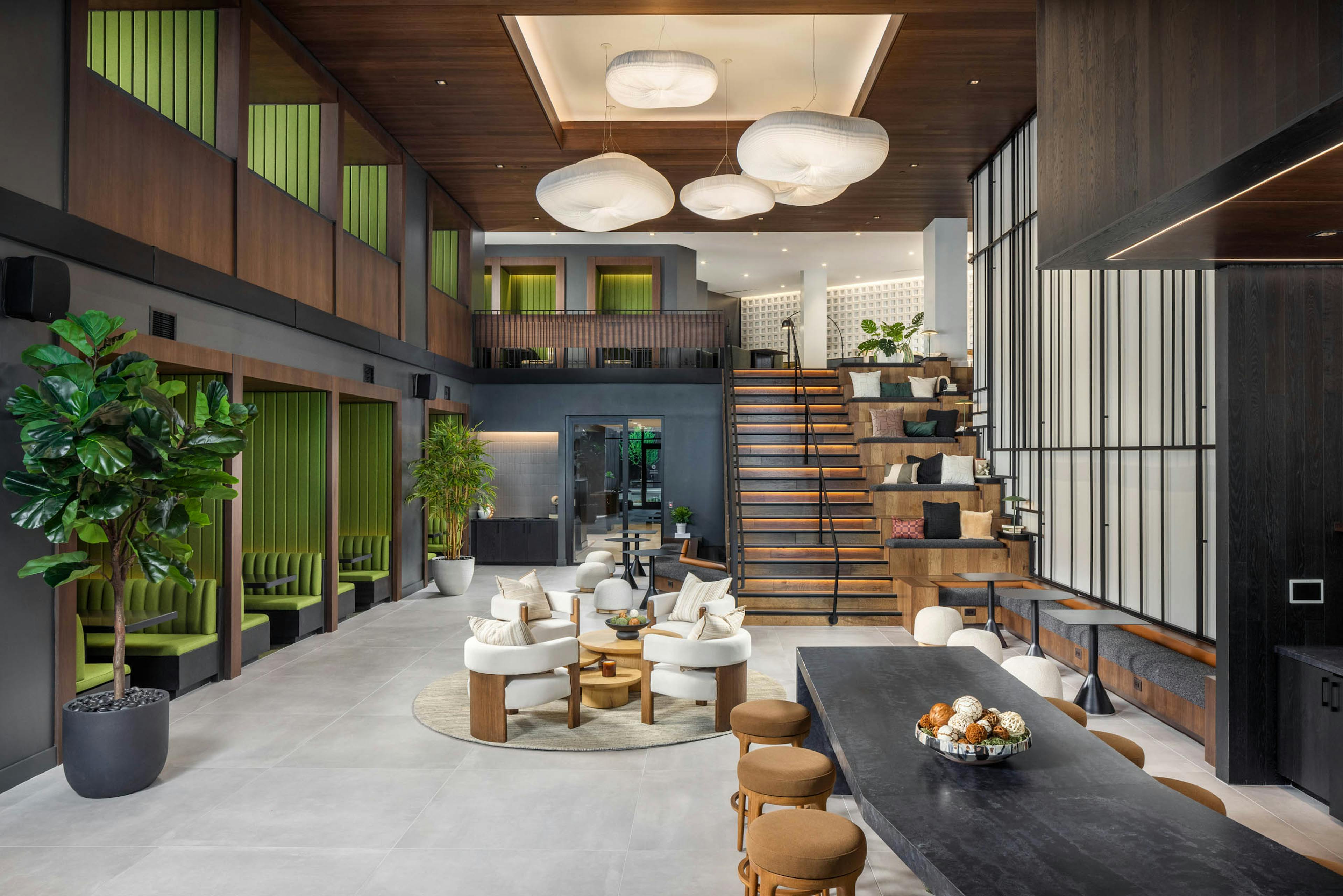A clubroom at AMLI Brookhaven with a bar top and stools with additional seating areas a flight of stairs up to a second level