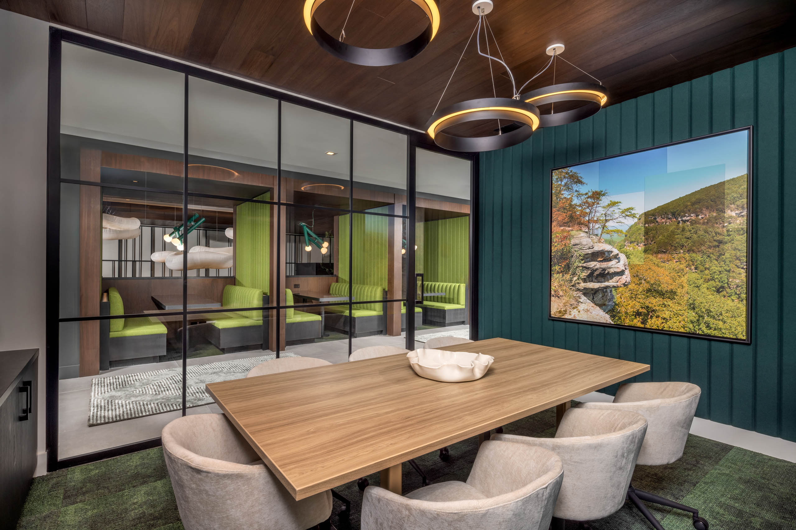 A conference room at AMLI Brookhaven apartments with a wood table and chairs and a large piece of wall art and a glass wall