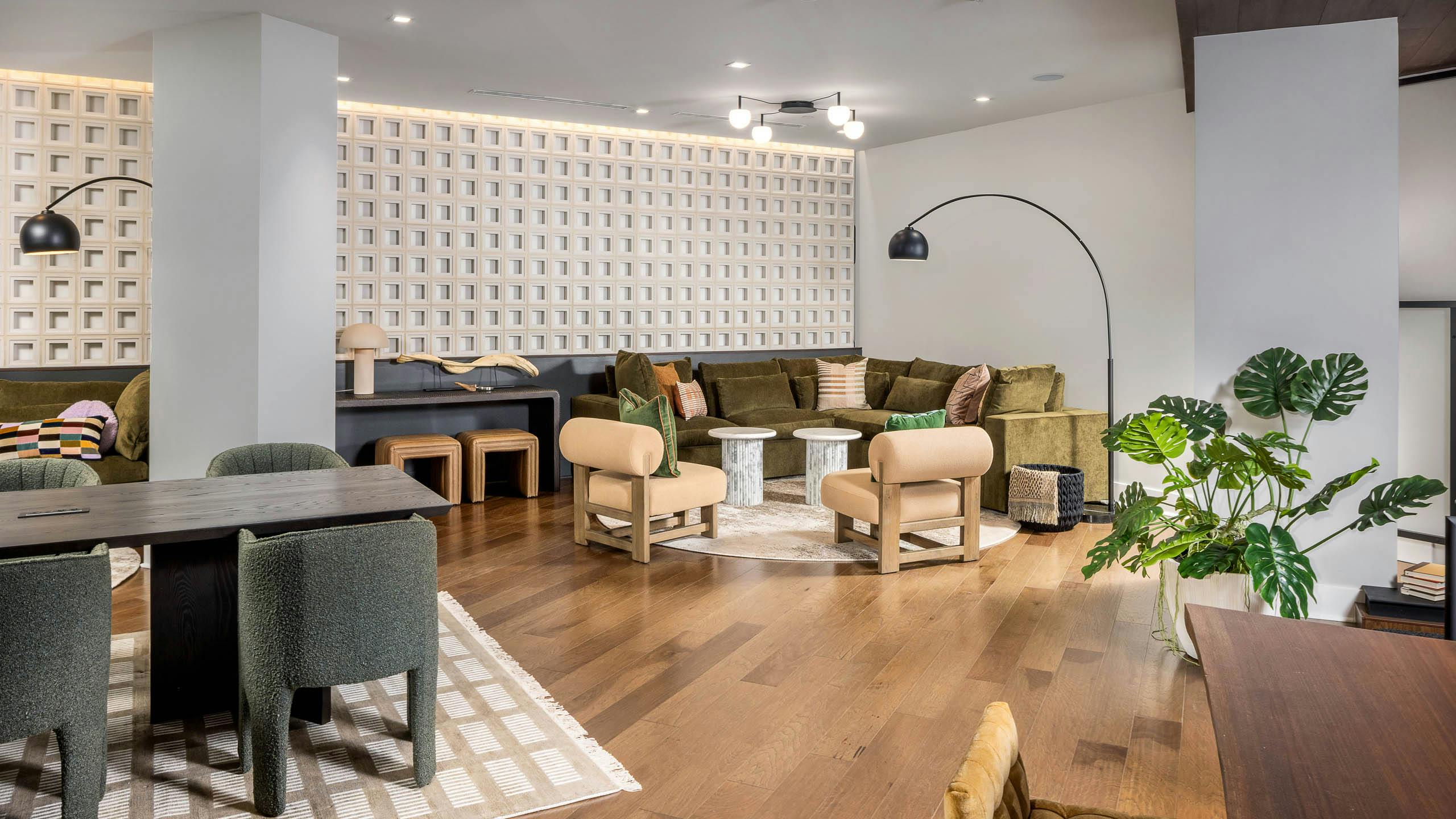 Interior view of a lounge at AMLI Brookhaven with hardwood flooring and floor plants and multiple seating areas with desks