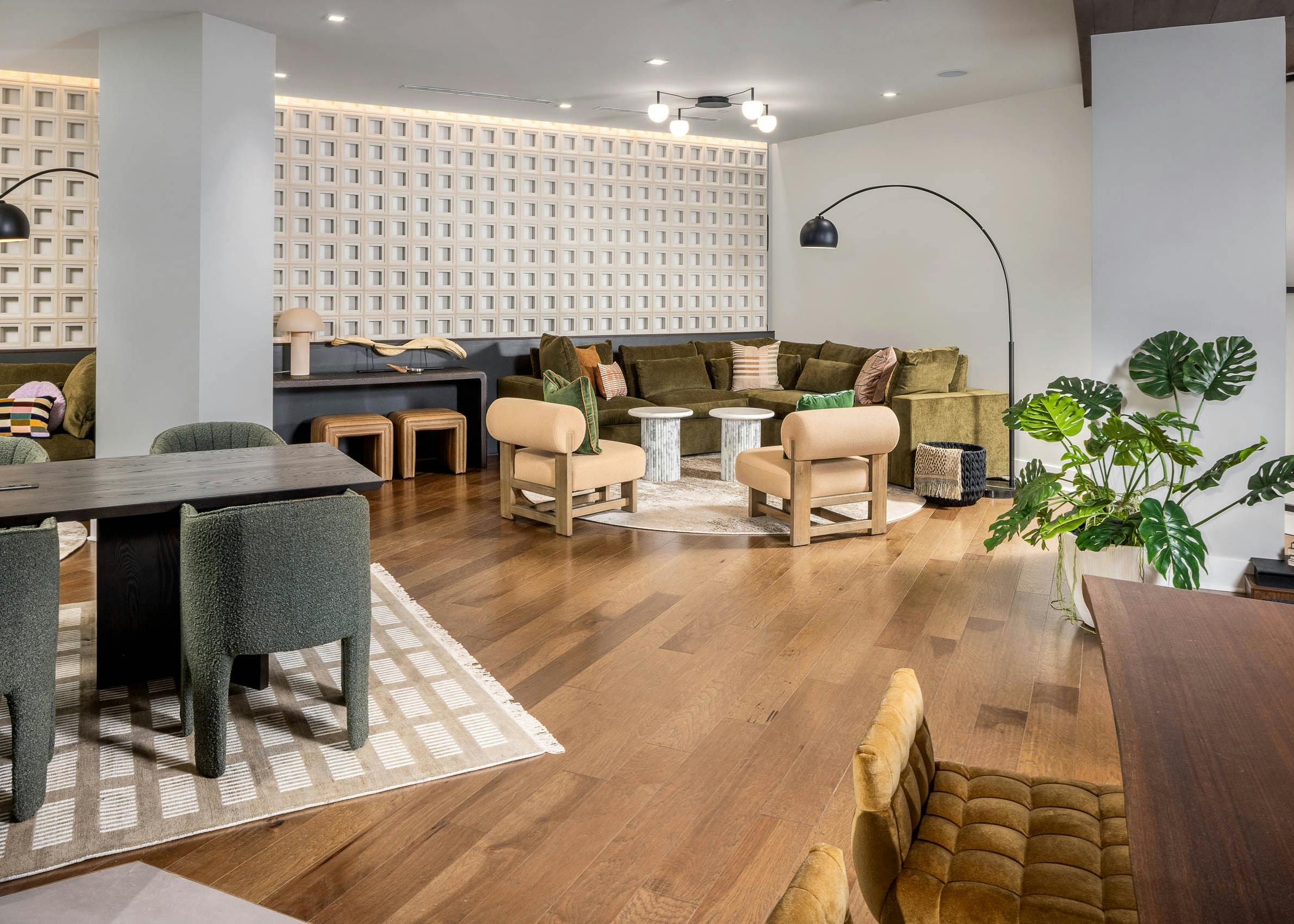 Interior view of a lounge at AMLI Brookhaven with hardwood flooring and floor plants and multiple seating areas with desks
