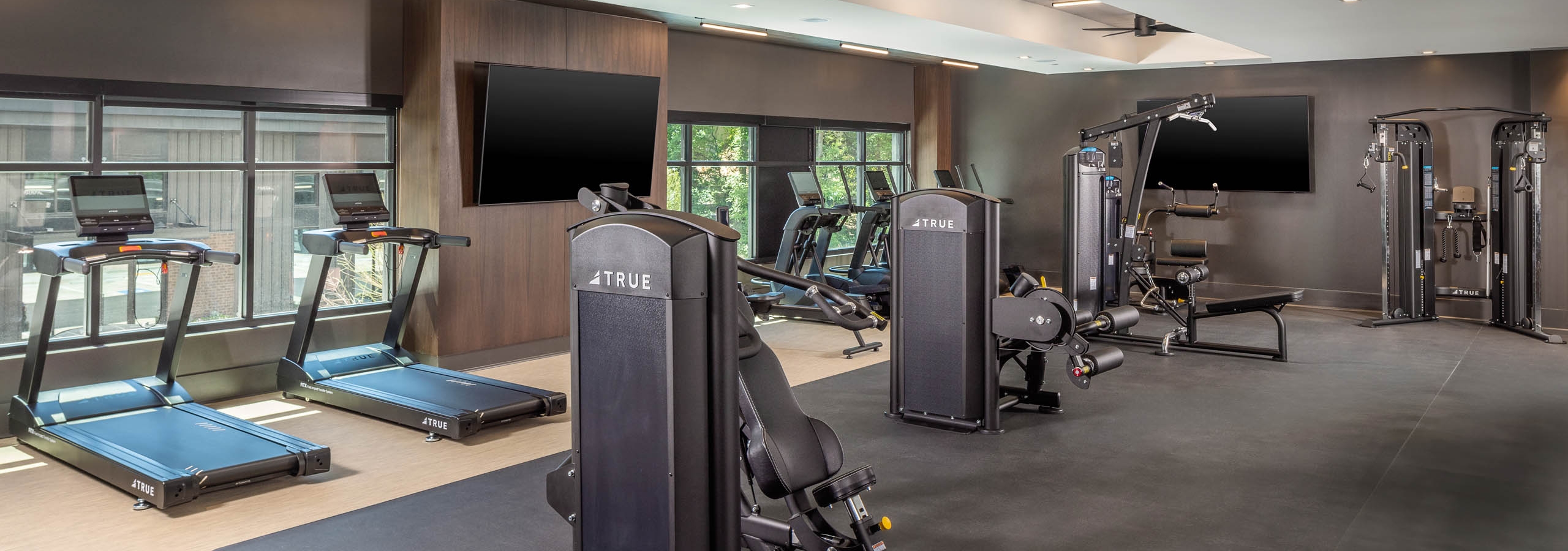 A fitness center at AMLI Brookhaven with a variety of cardio and strength training equipment and a flat screen television