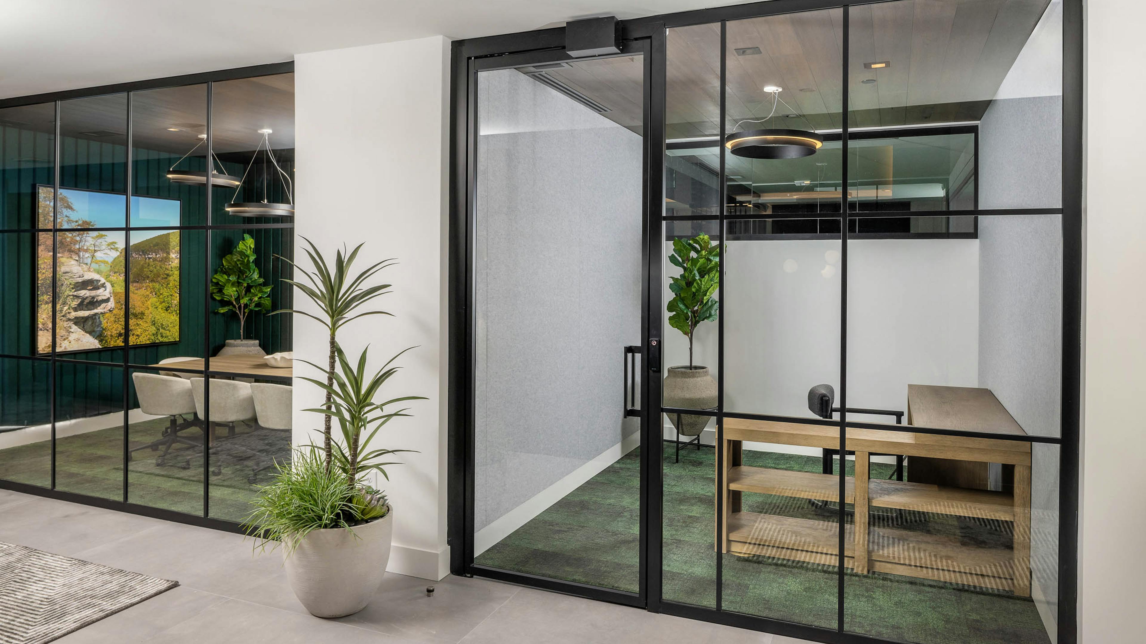 Private office and conference room at AMLI Brookhaven with floor to ceiling windows with black and green carpeting and wood furniture
