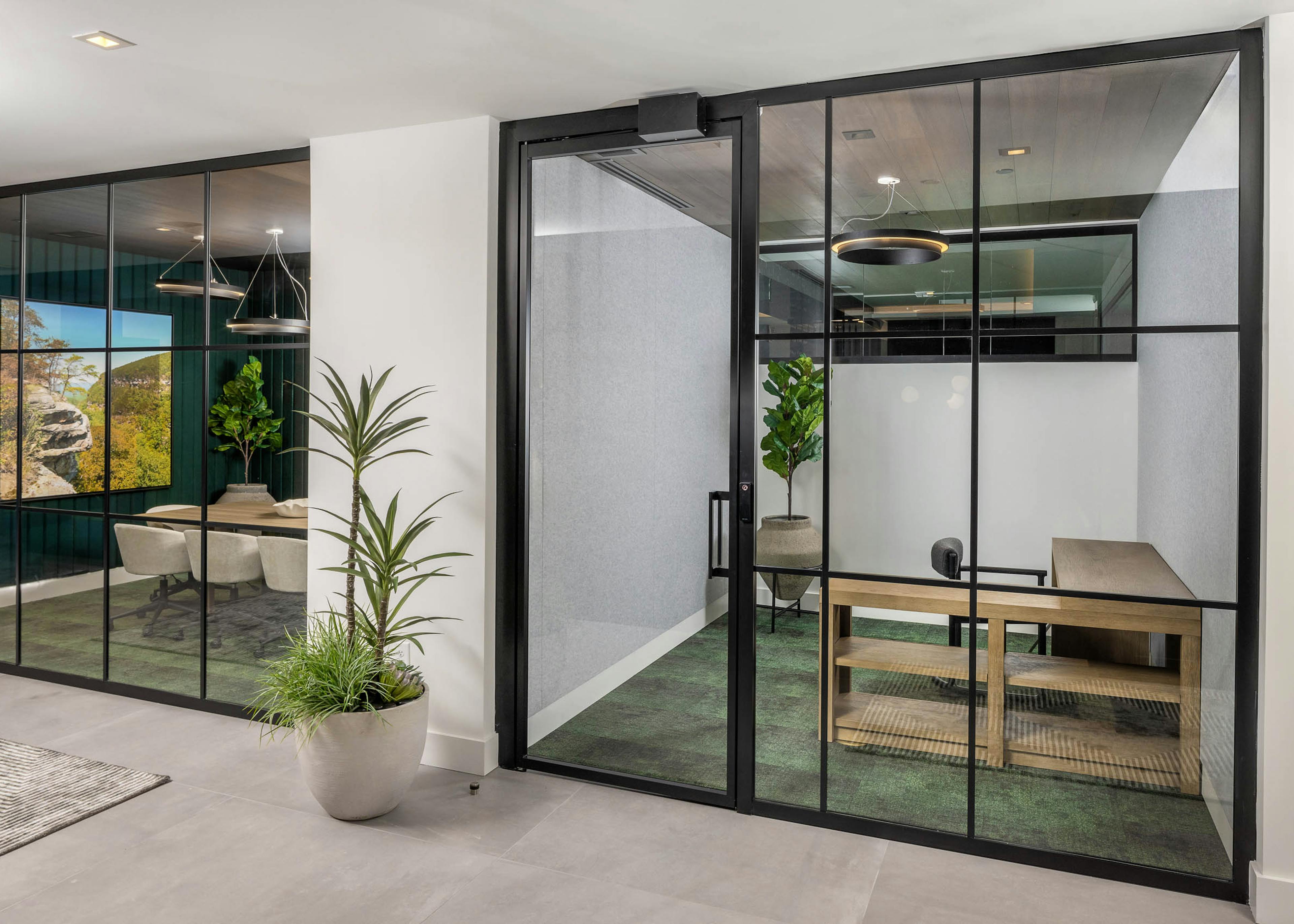 Private office and conference room at AMLI Brookhaven with floor to ceiling windows with black and green carpeting and wood furniture