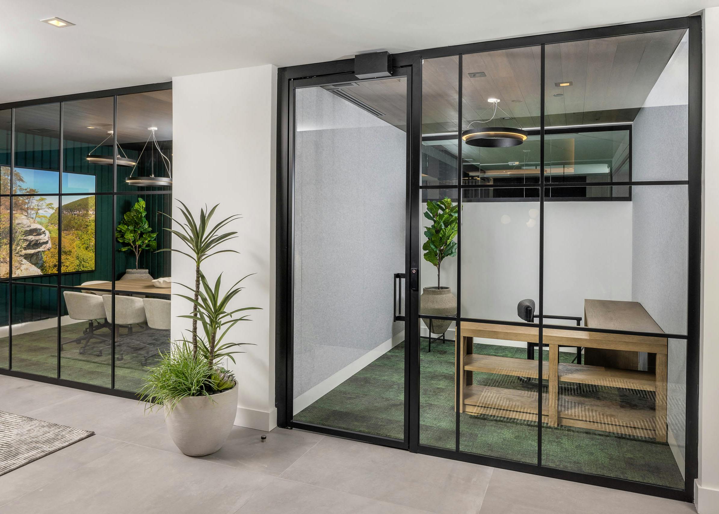 Private office and conference room at AMLI Brookhaven with floor to ceiling windows with black and green carpeting and wood furniture