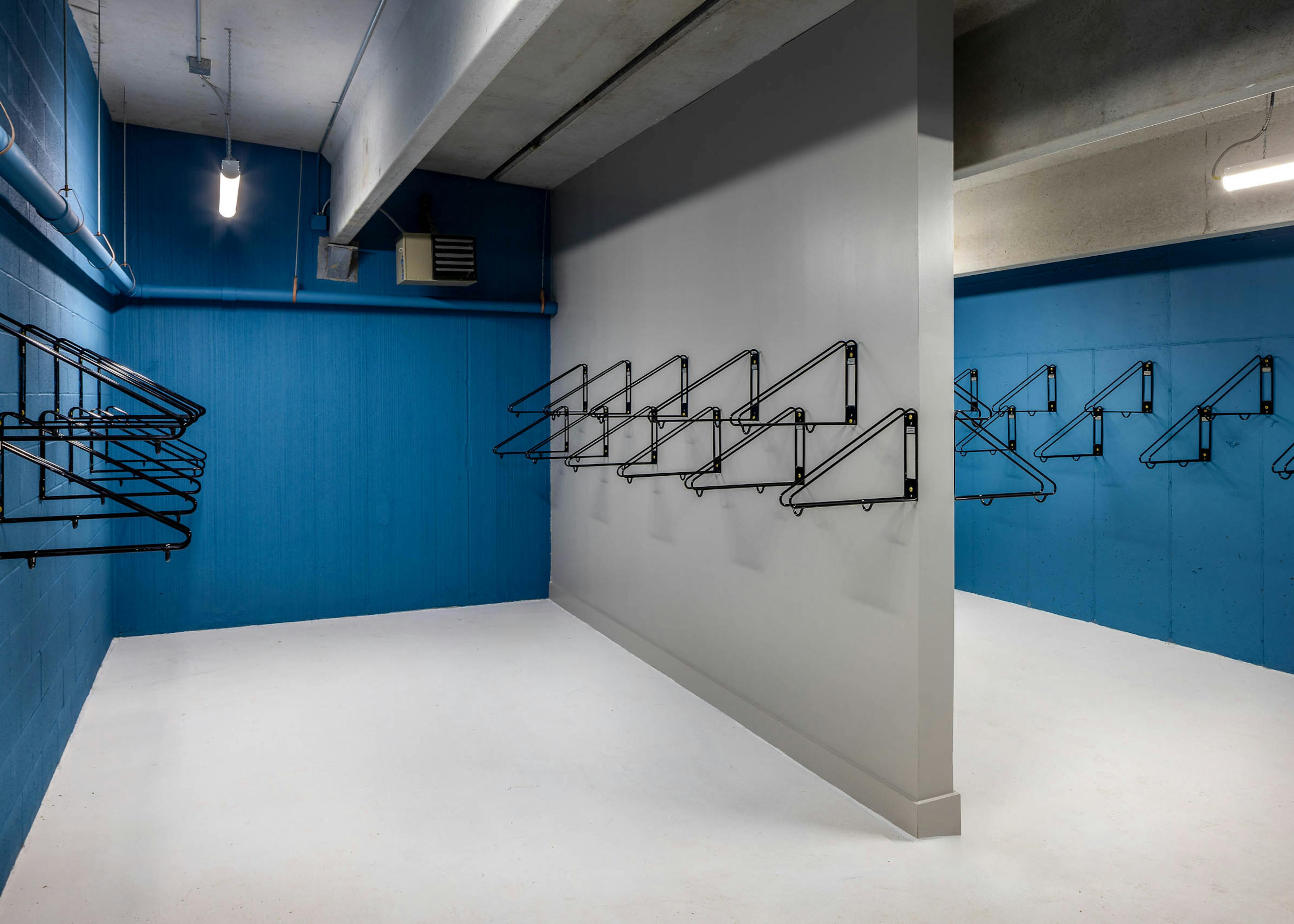 An interior view of a bike storage room at AMLI Brookhaven with several wall mounted metal bike racks and blue cement walls