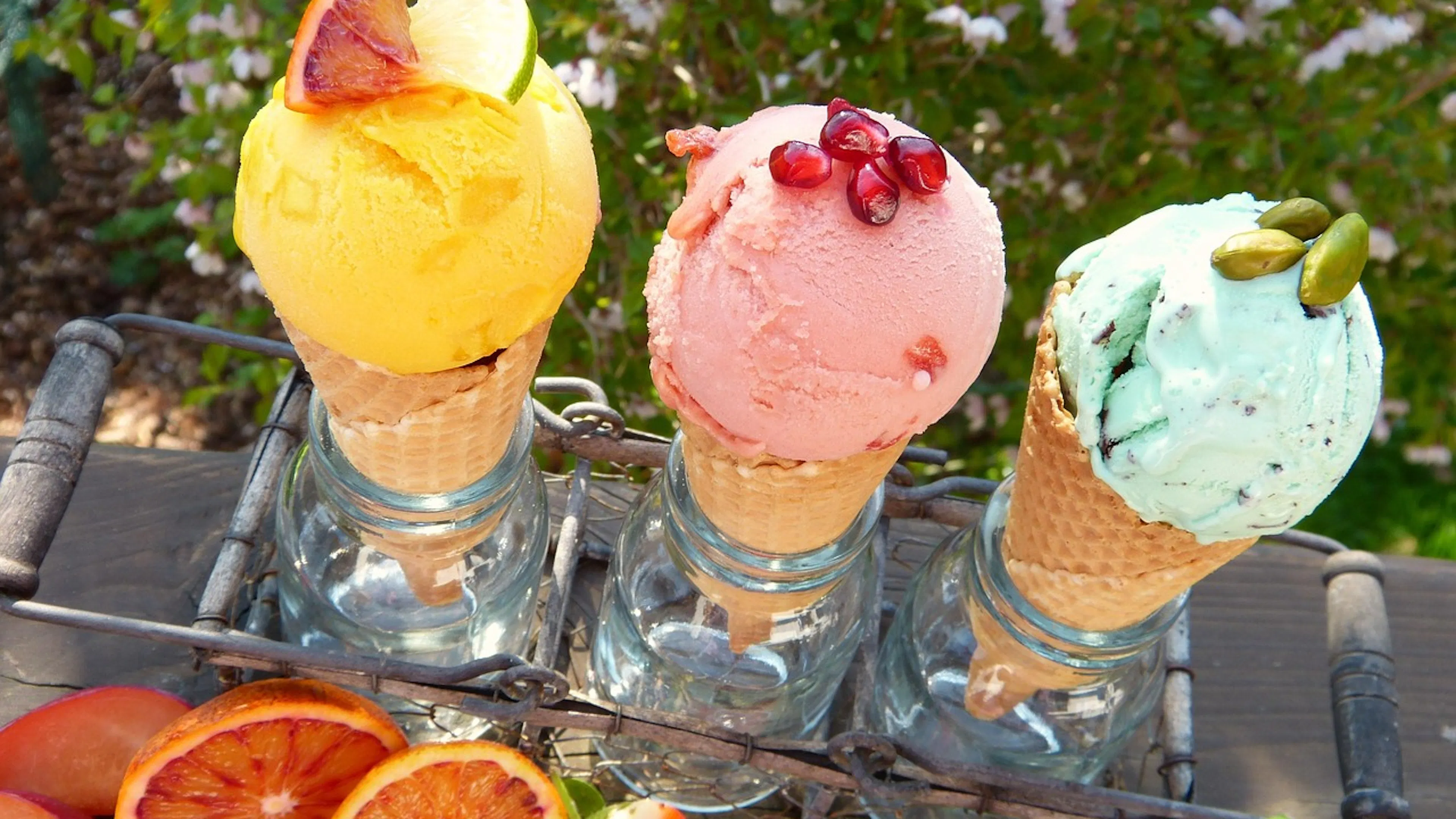 ice cream cones in yellow, pink and green in wire holder with fruit